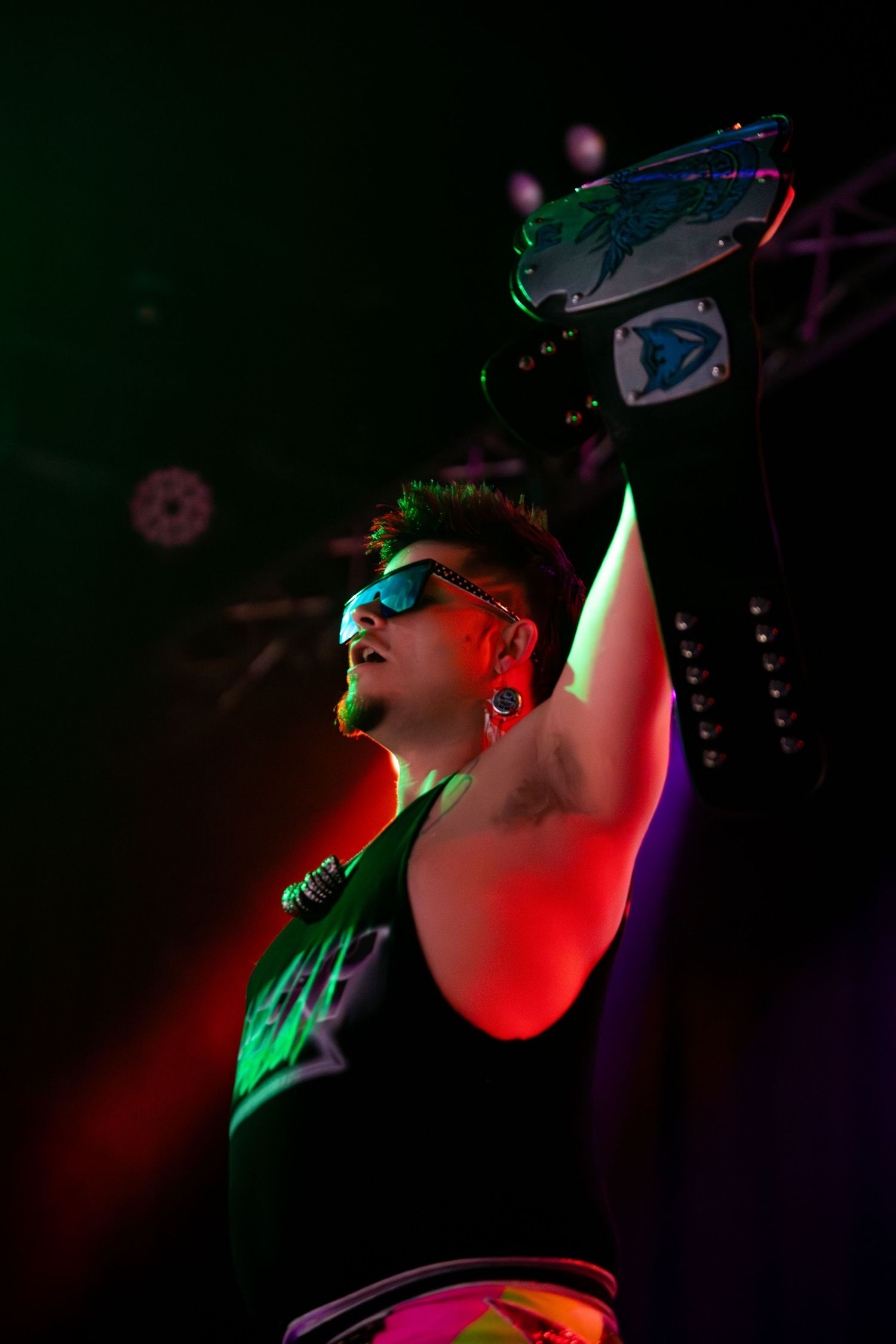 Performer singing on stage illuminated by colorful red and green lighting effects.