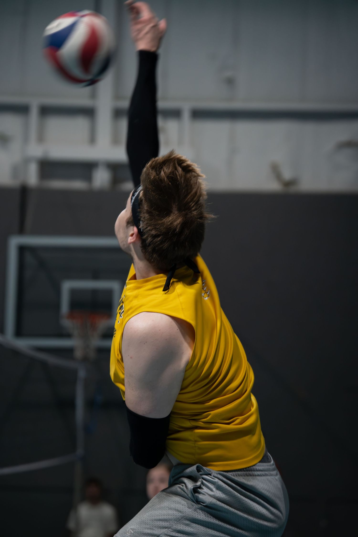 Athlete in yellow top practicing volleyball moves in a gym setting.
