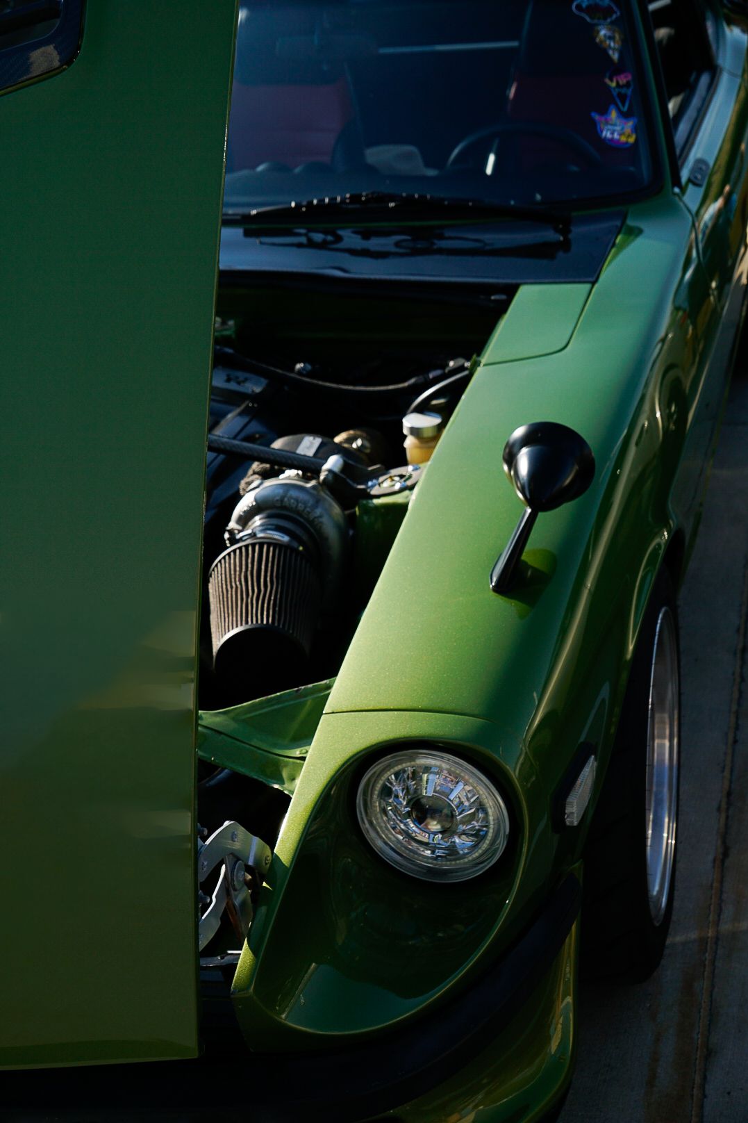 Vintage lime green sports car photographed from the front quarter panel showing classic styling.