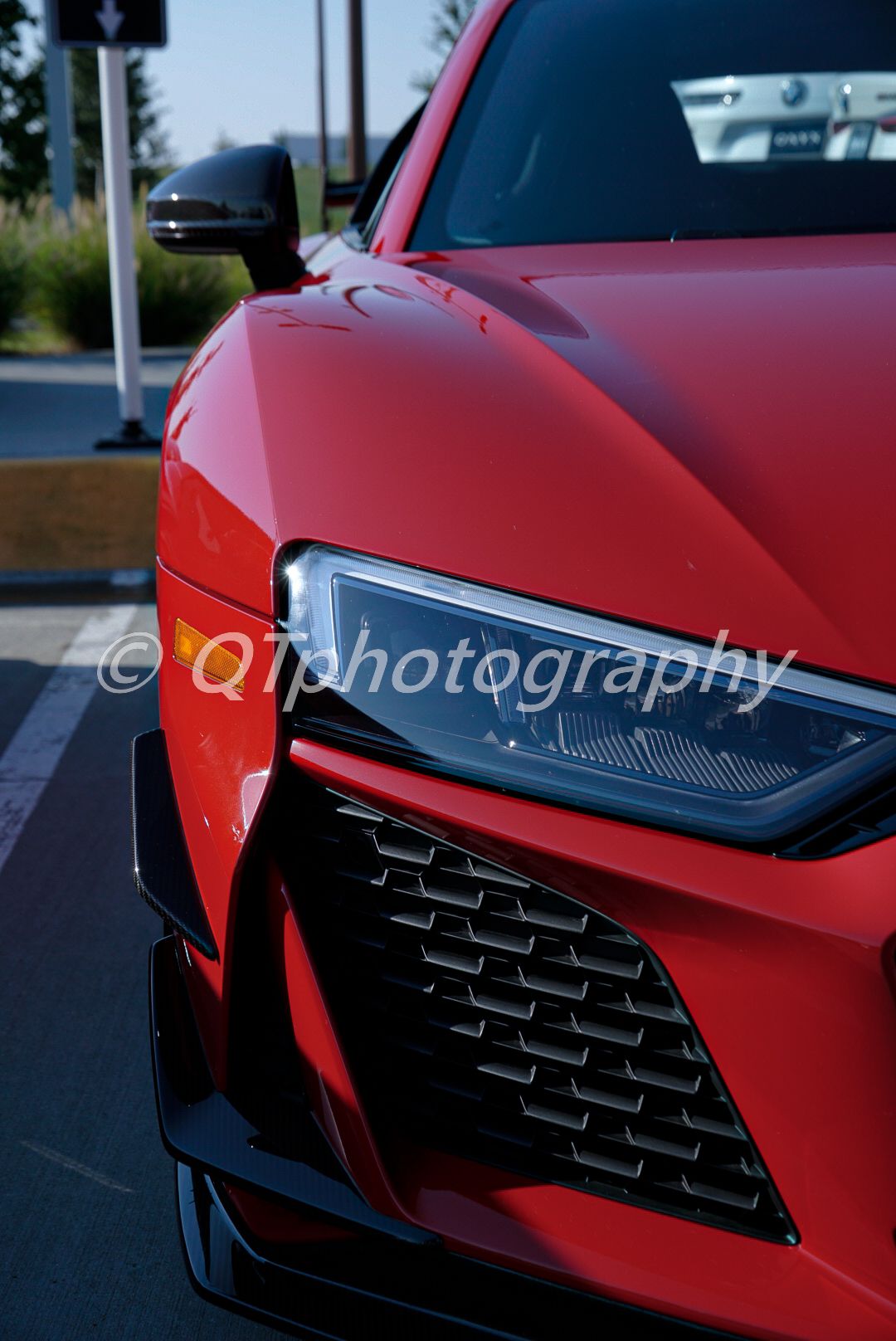 Front view details of a red sports car showing aggressive grille and headlight design.