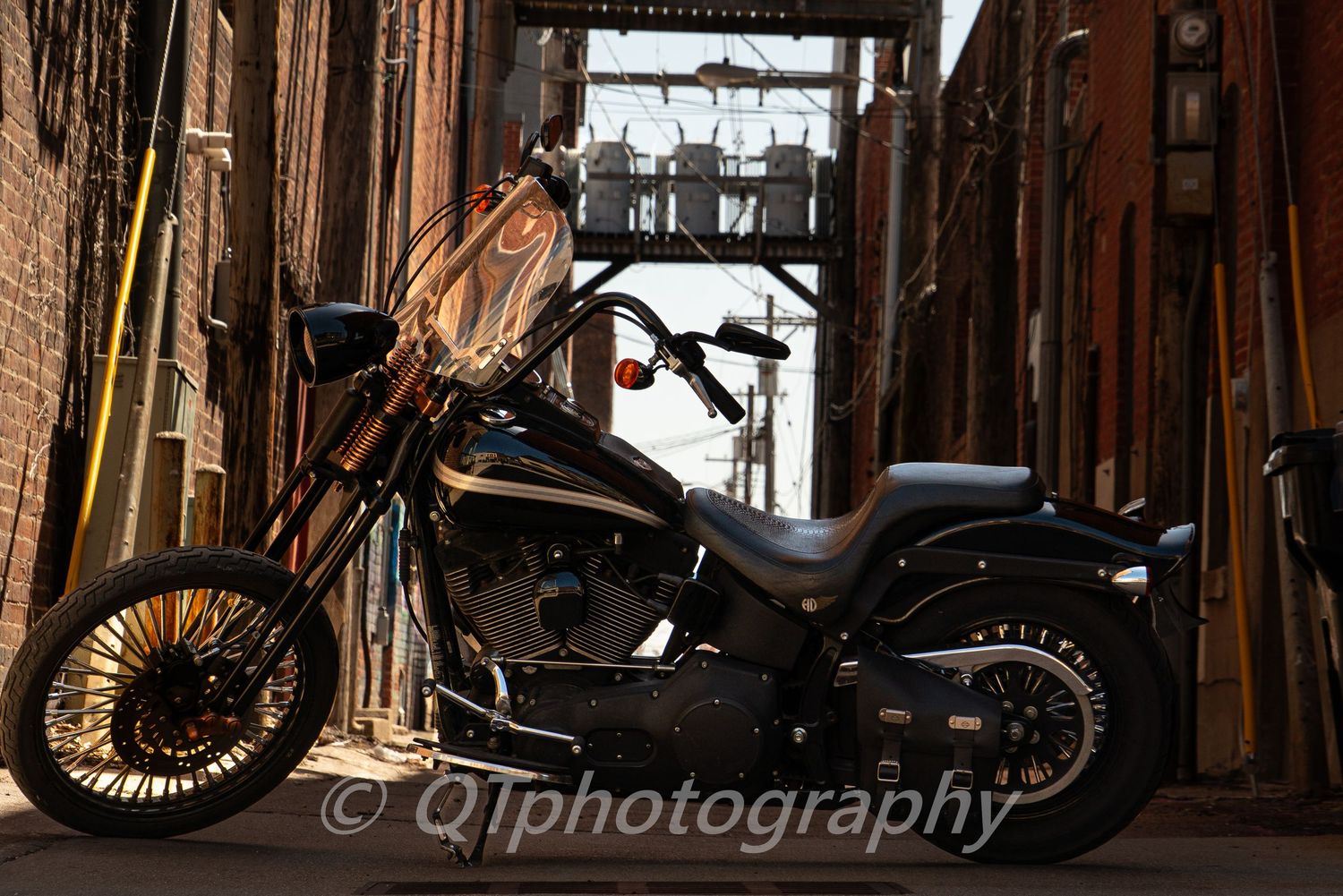 Black motorcycle parked in a dimly lit brick corridor with industrial architectural elements.