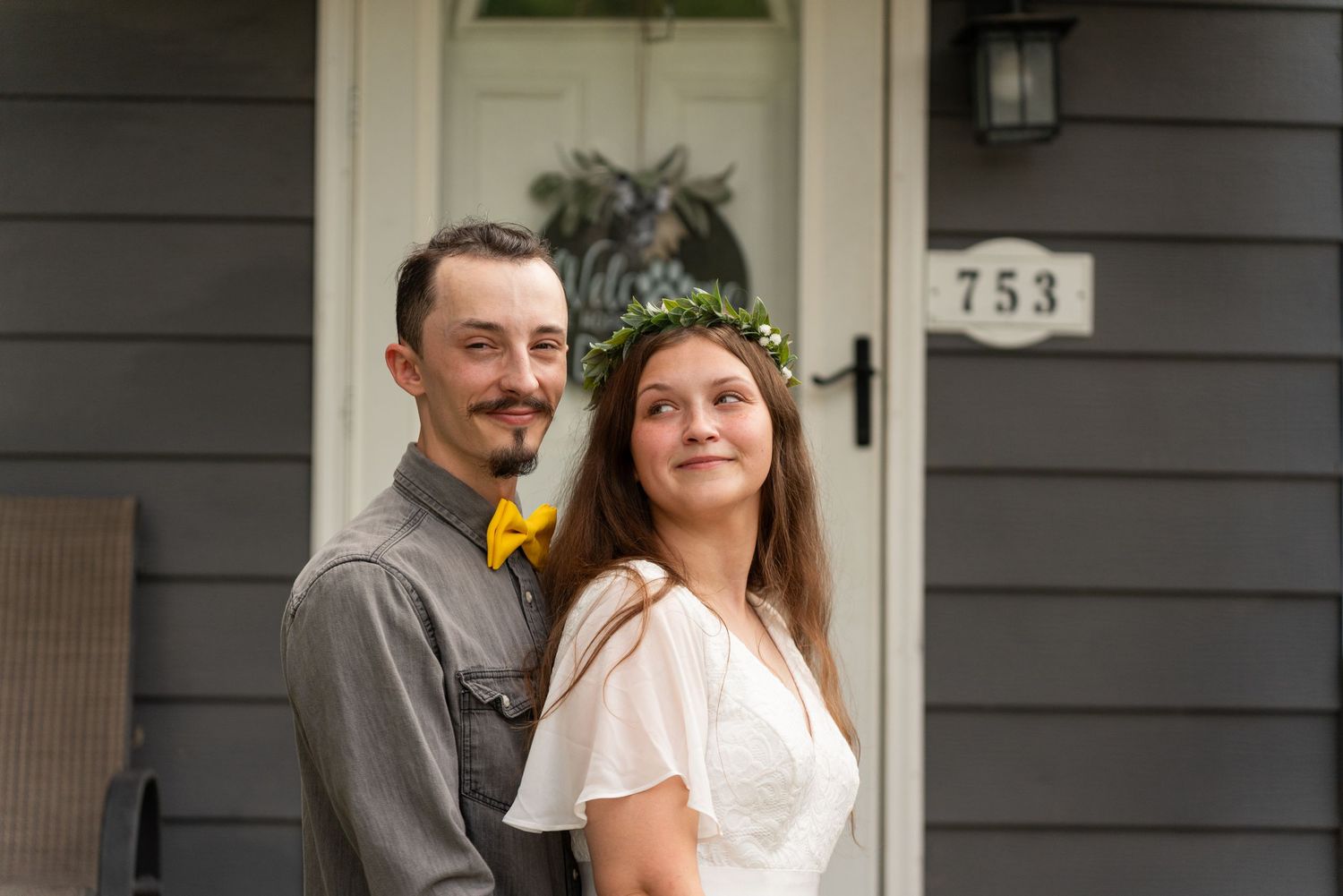 A couple stands together on their front porch near house number 753.