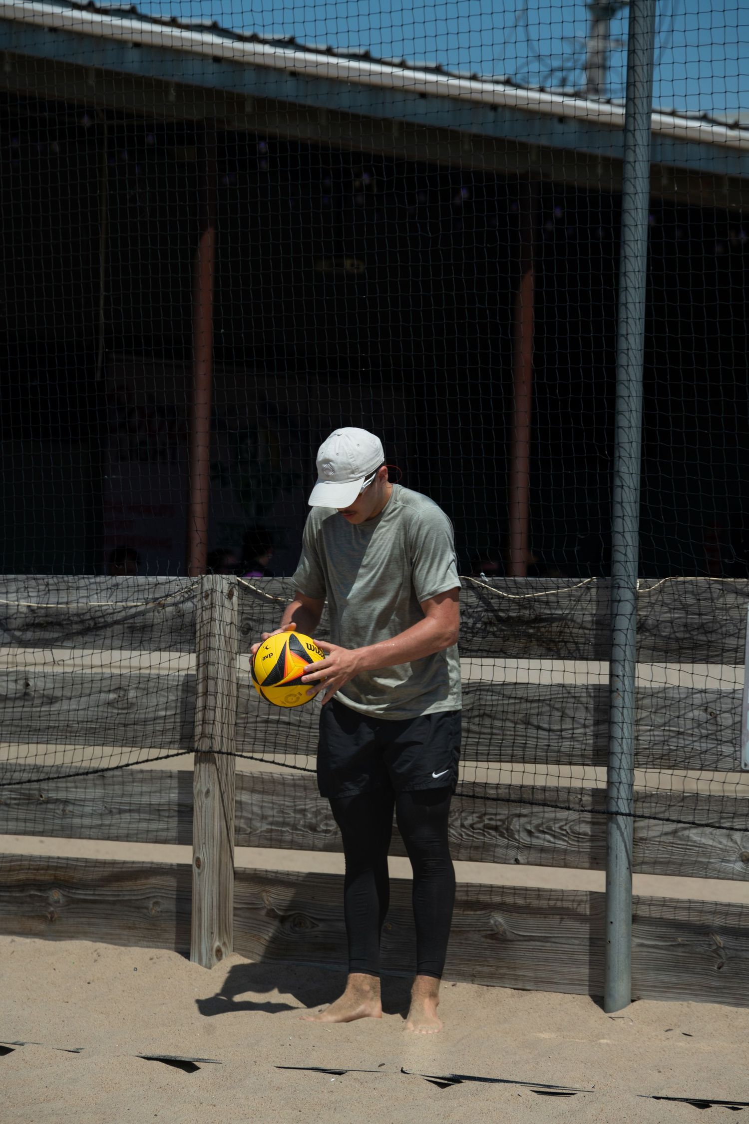 A beach volleyball player prepares to serve the ball on a sandy court.