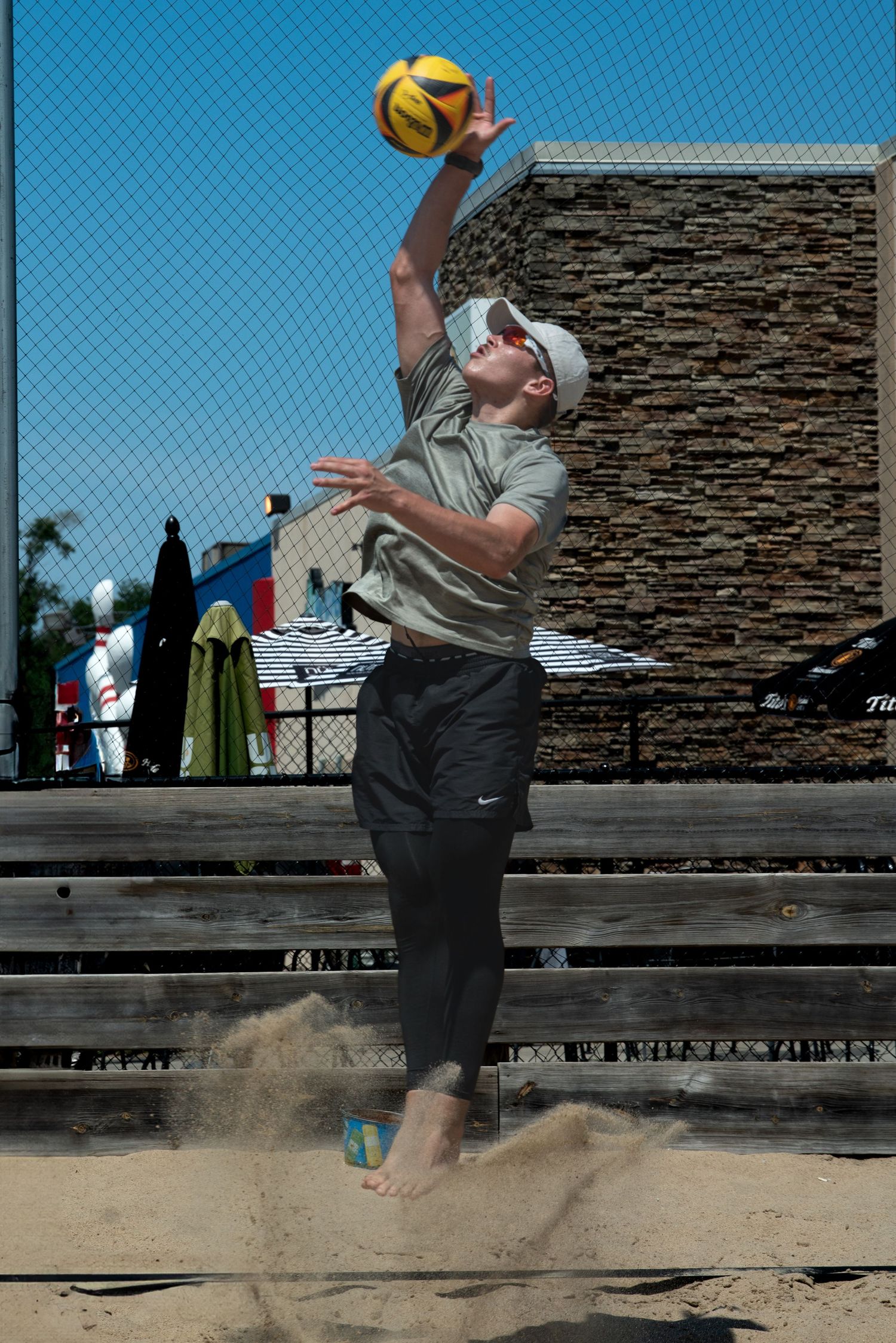 Action shots of a player jumping to hit a volleyball on a beach court.