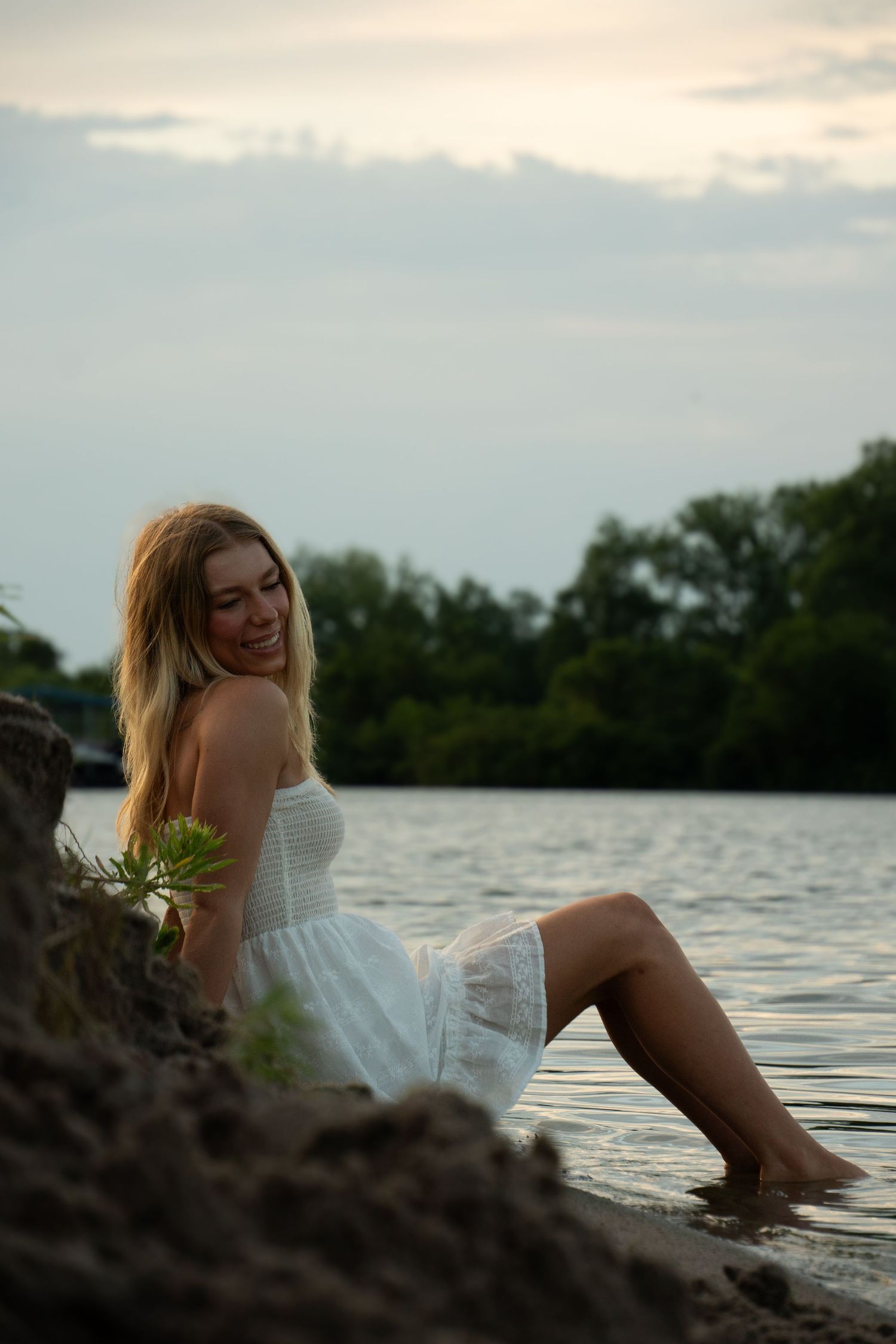 Dreamy waterside portrait in white dress during sunset.