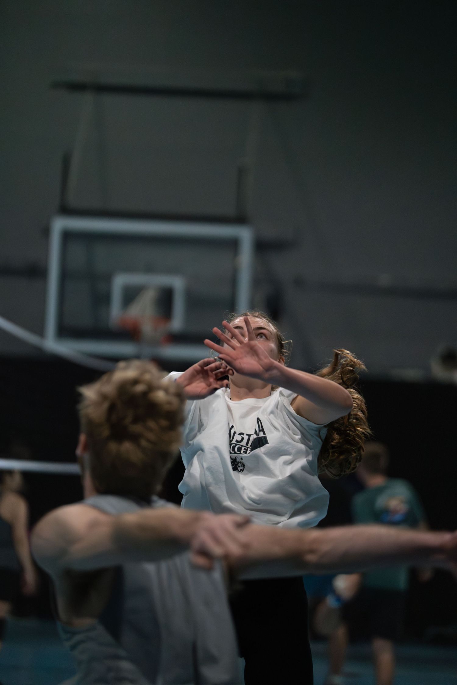 Athletes practice defensive volleyball moves in an indoor sports facility.