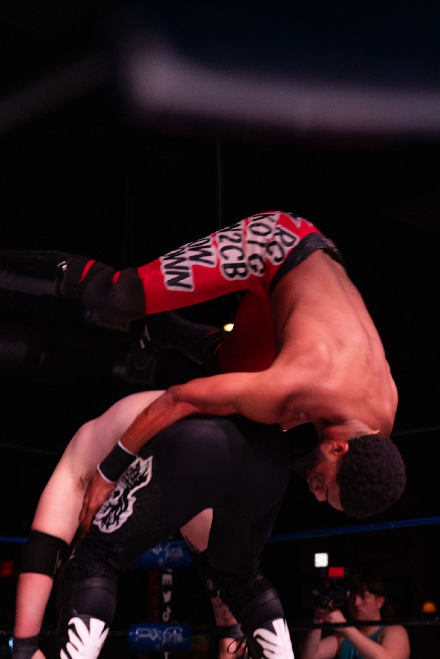 Dynamic wrestling action shot shows a high-impact move being executed in sequence.
