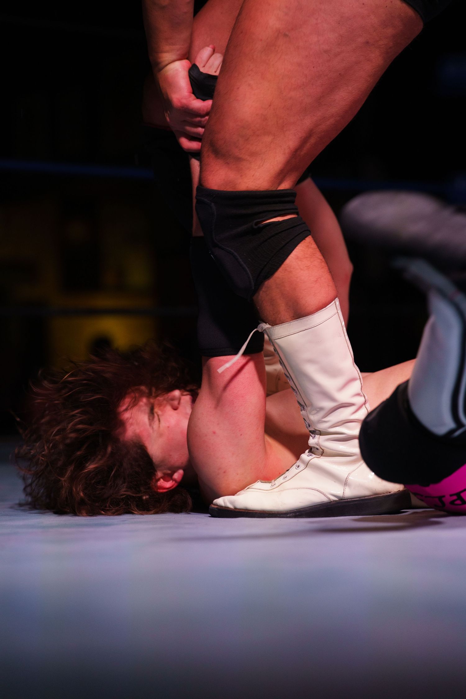 A sequence of wrestling moves being performed on a mat showing a person being pinned down with a foot.
