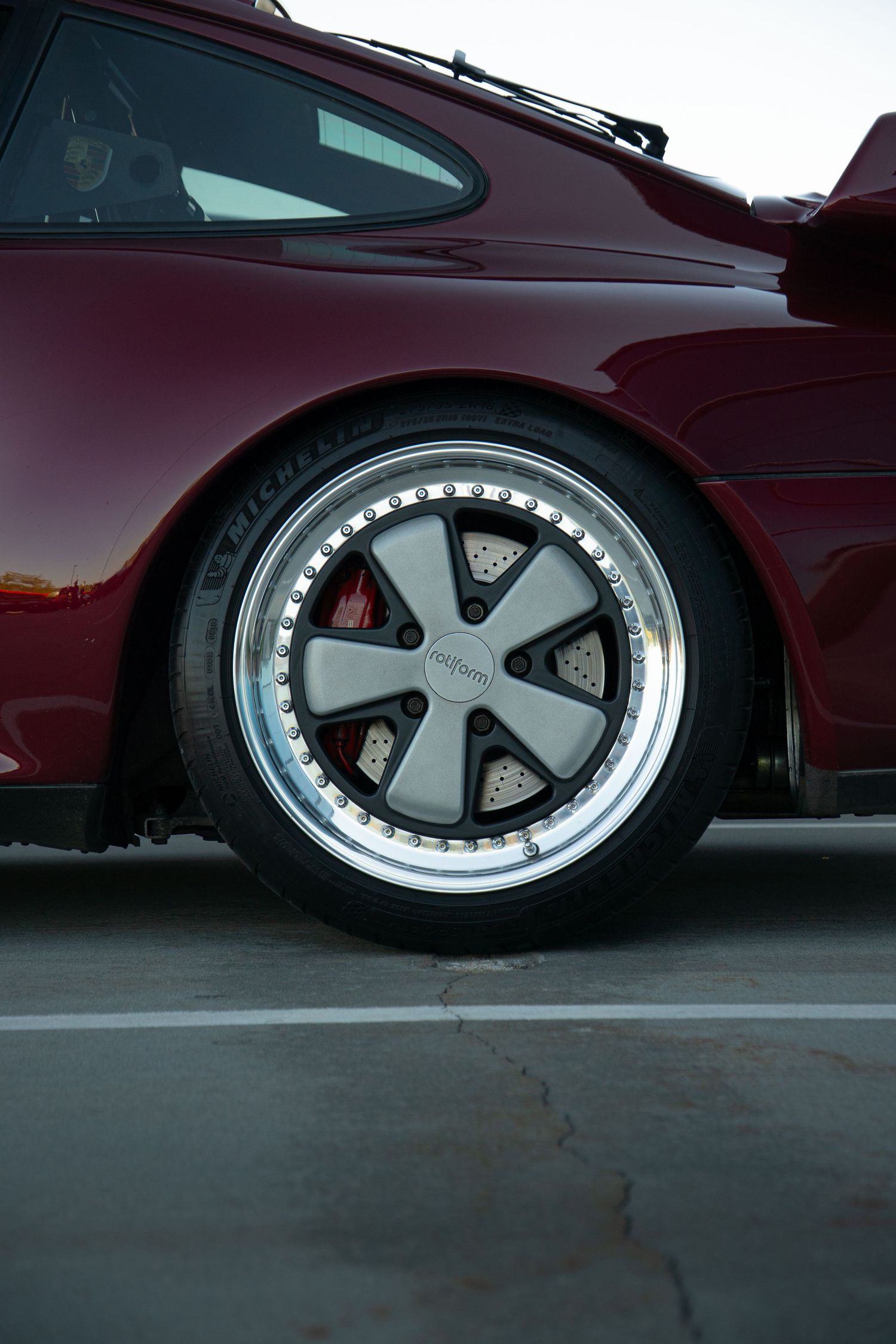 Low angle view of custom wheels on a burgundy lowered vehicle.