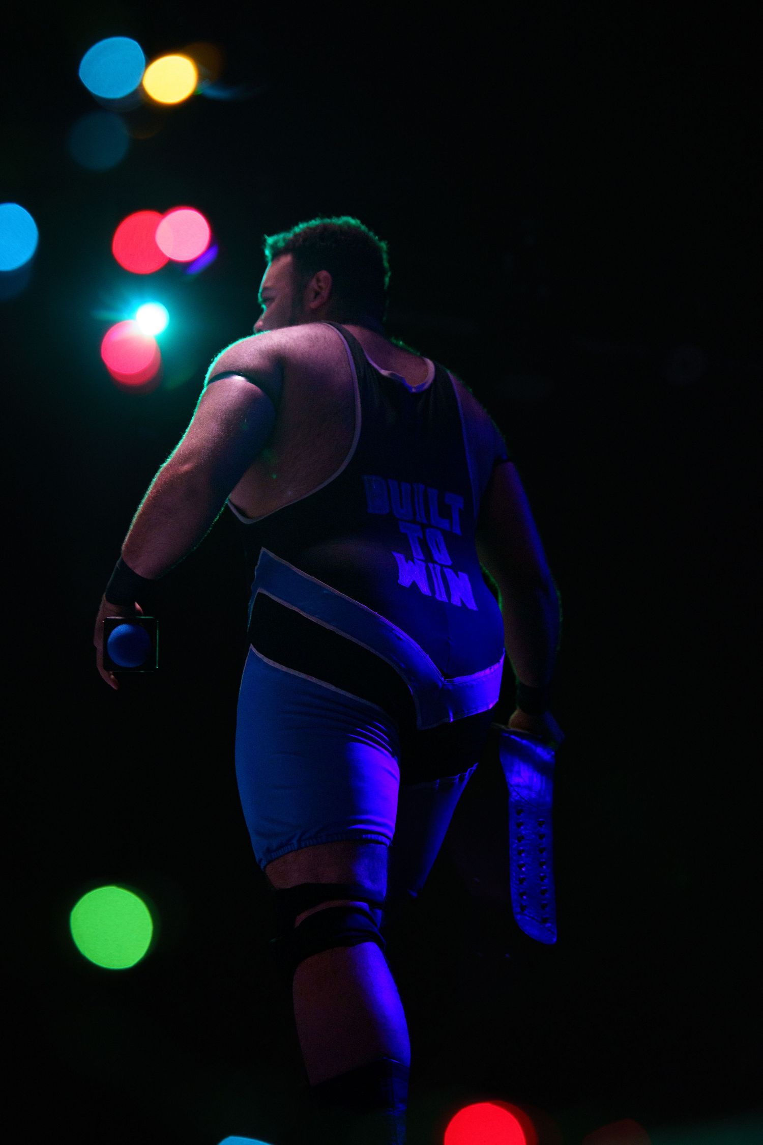 Silhouetted dancers perform in a dark nightclub setting with colorful bokeh lights creating a vibrant atmosphere.