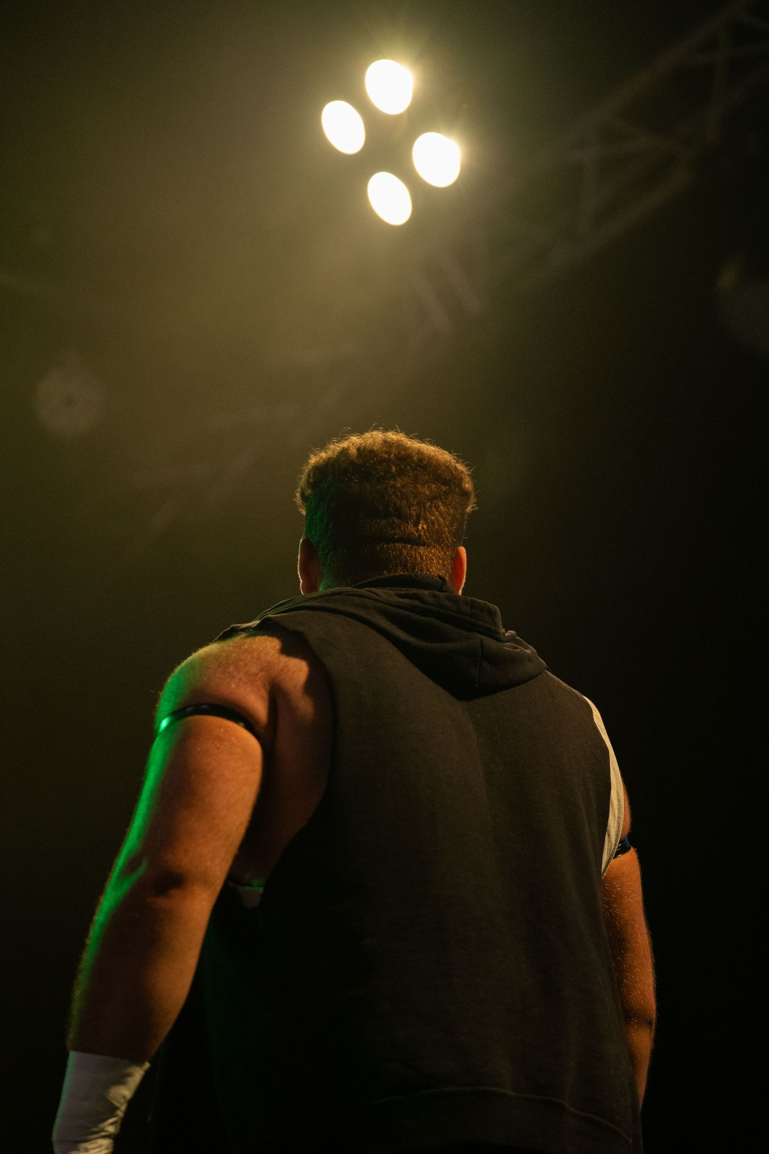 Silhouetted figure stands under spotlights during a dramatic performance.