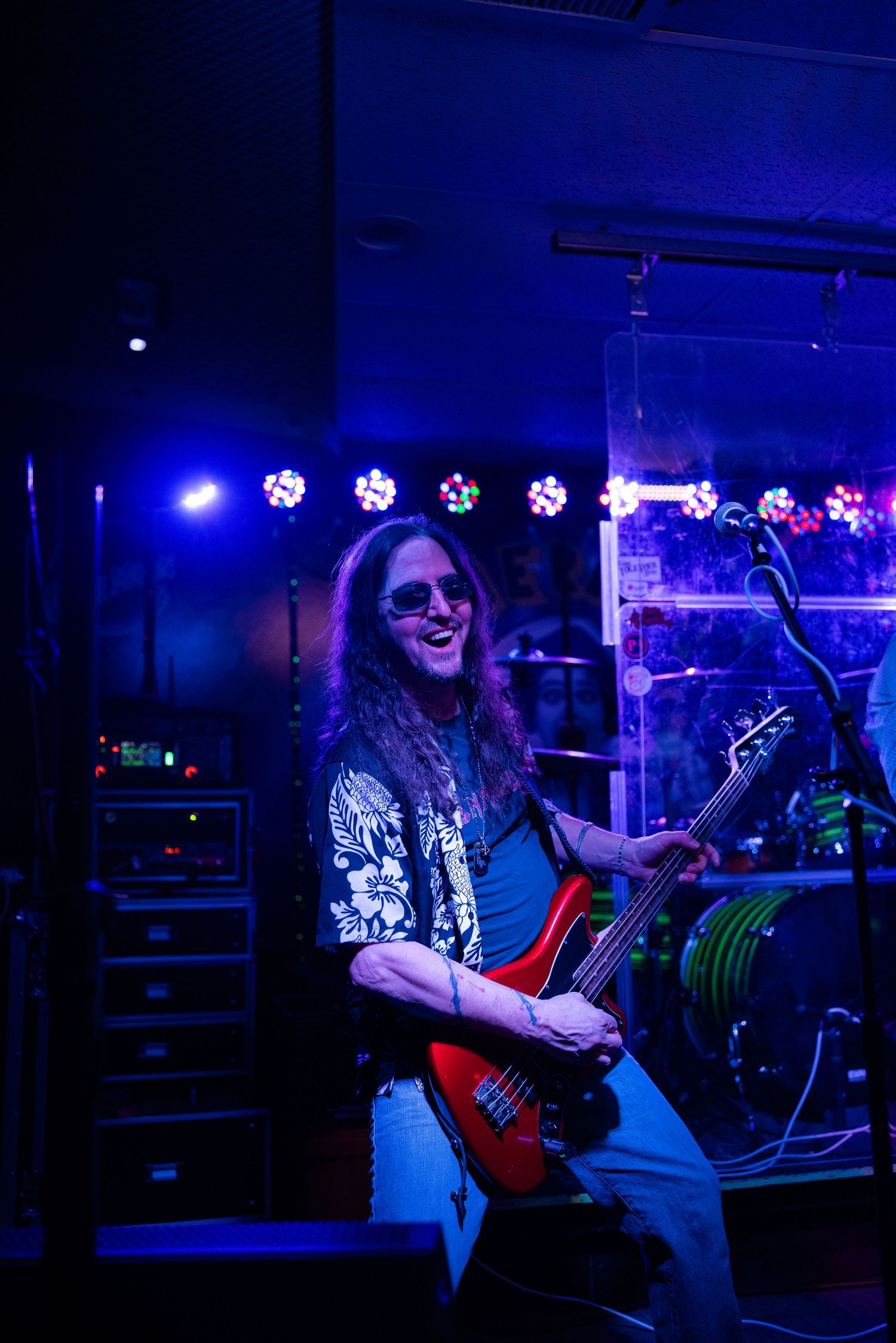 Musicians perform with guitars under blue stage lighting at a concert venue.