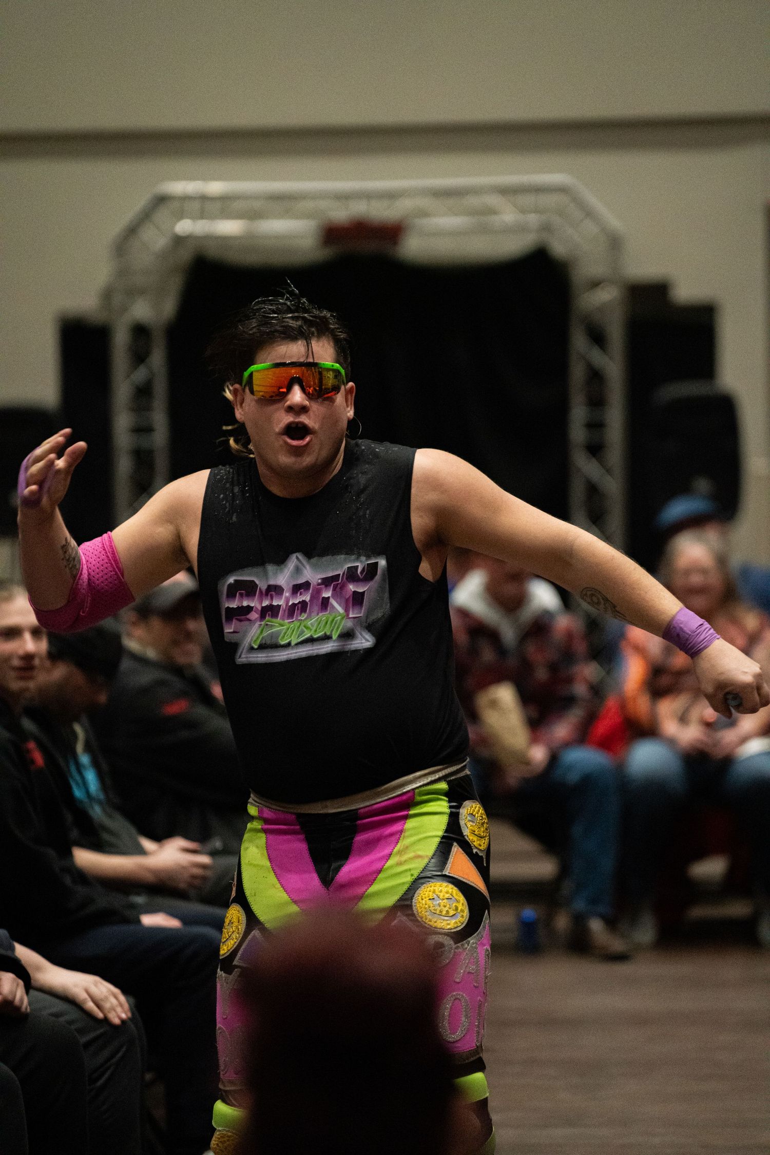 Performer in neon costume strikes dynamic pose during indoor show.