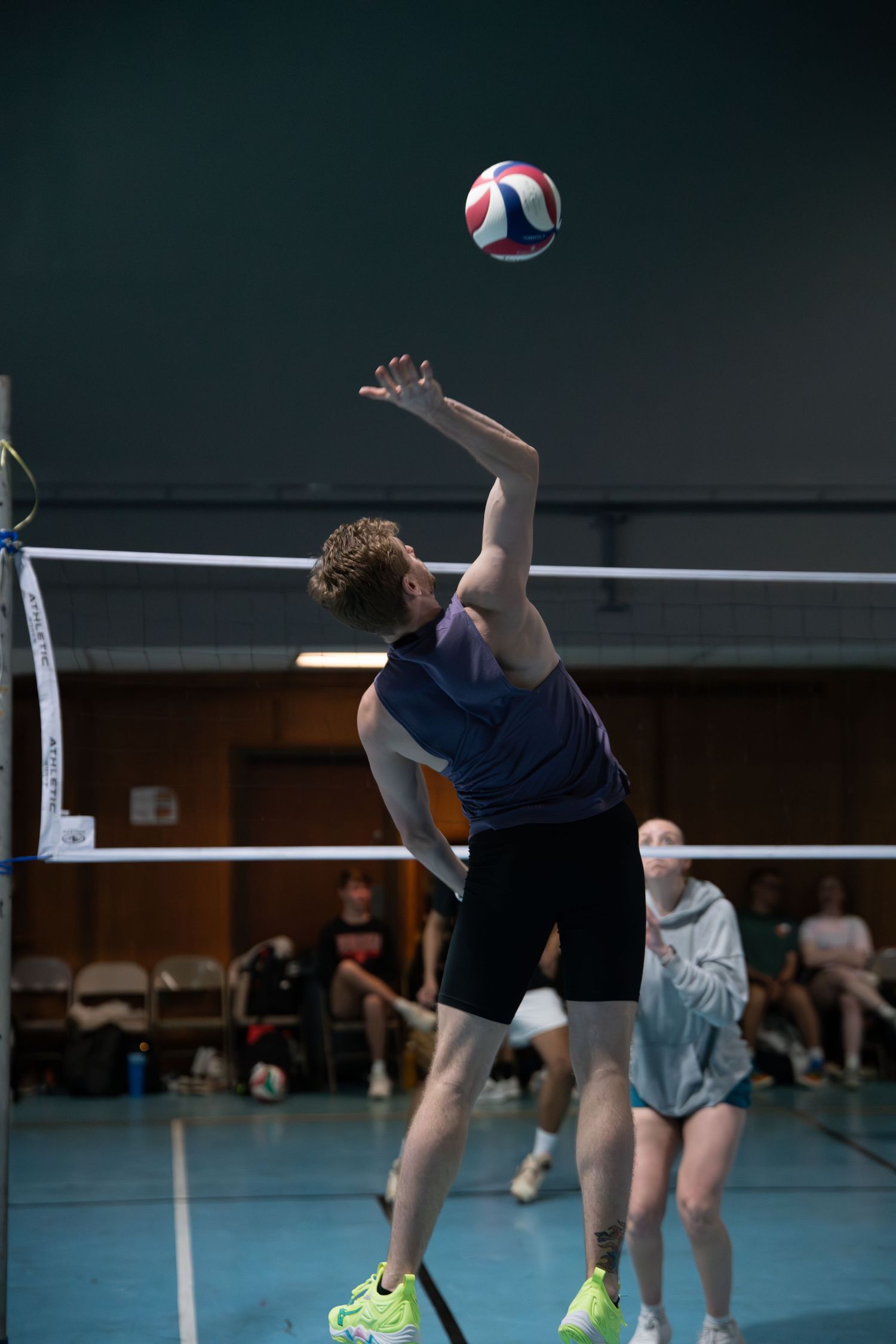 Athletes practice volleyball techniques with one player leaping to spike the ball.