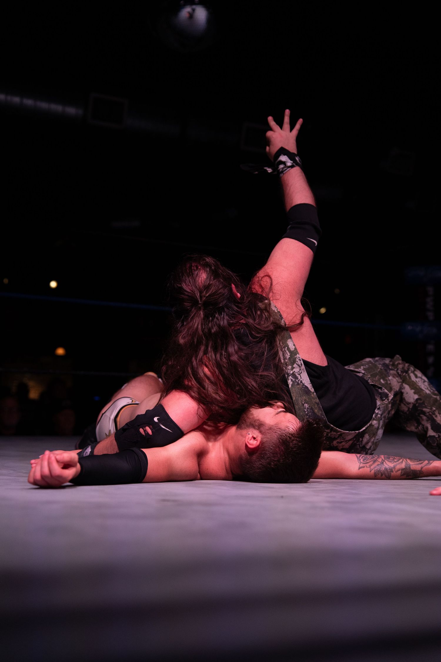 Wrestling match concludes with competitors on the mat under dramatic spotlights.