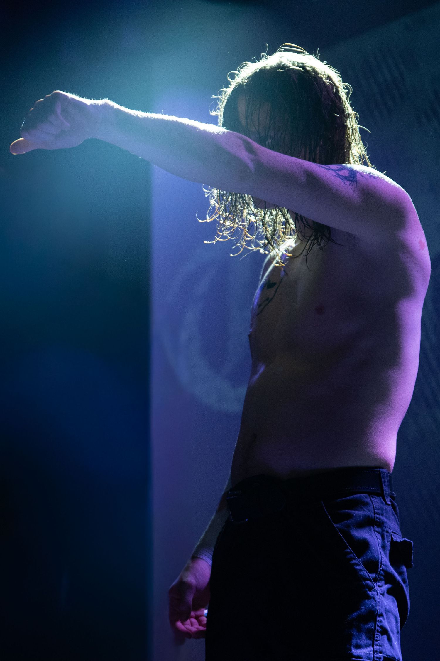 Dramatic silhouette of performer backlit by blue stage lighting.
