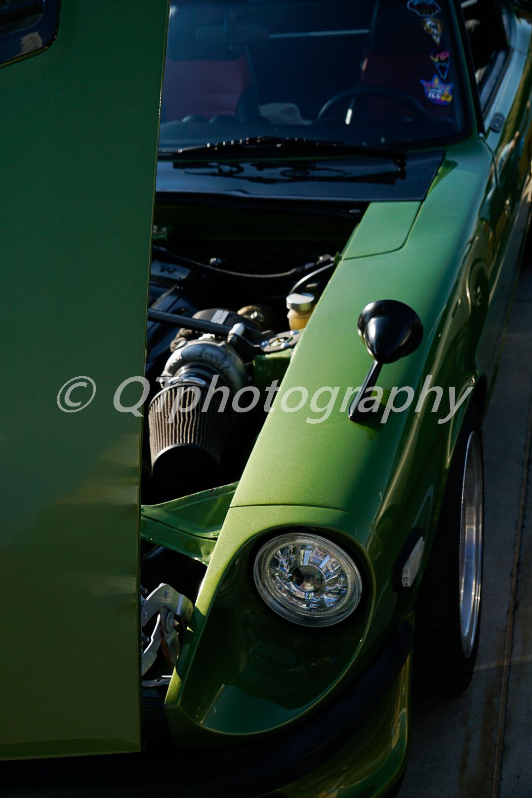 Sleek green sports car photographed in dramatic low lighting showing curved bodywork.
