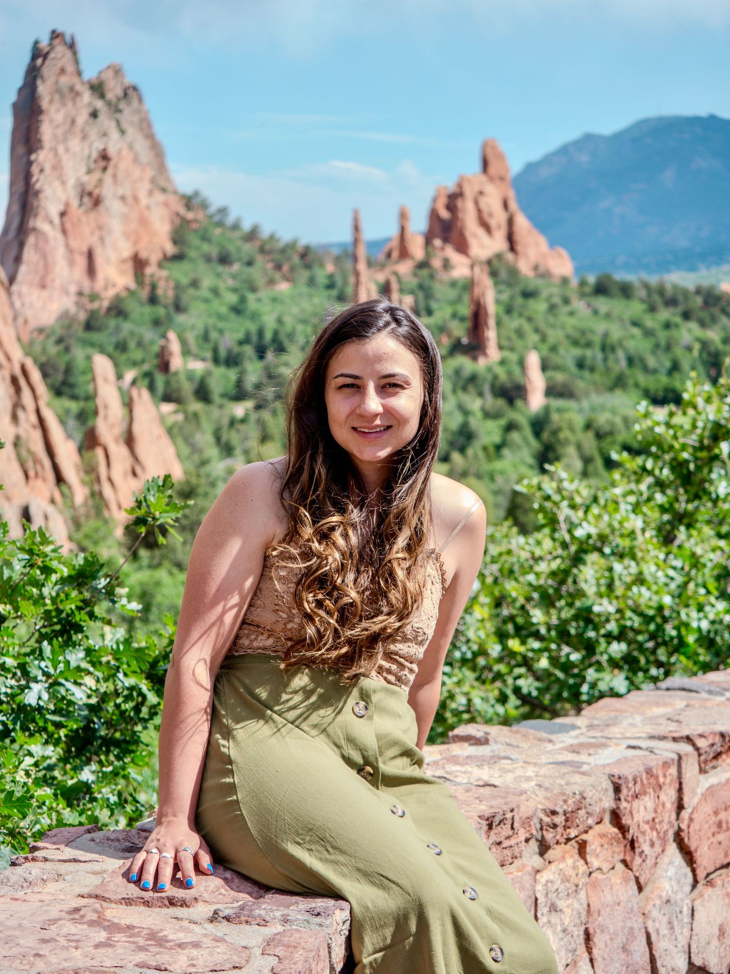 Red sandstone rock formations rise dramatically against blue sky at Garden of the Gods park in Colorado Springs.