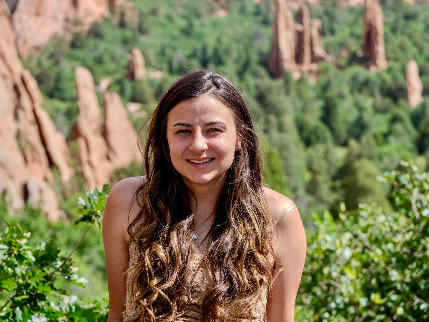 A person smiles while enjoying the scenic view of red rock formations at Garden of the Gods in Colorado.