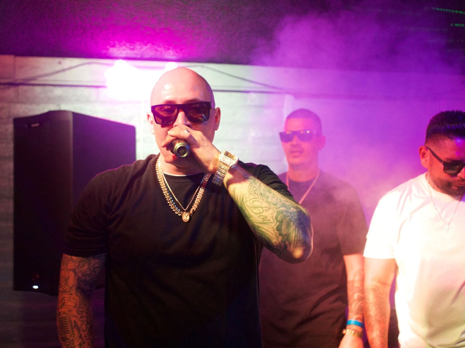 A series of people in a hazy purple-lit nightclub environment performing or partying together.