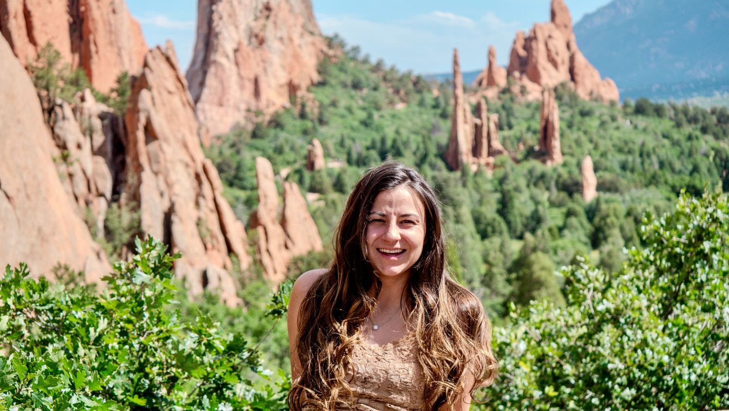 A visitor enjoys the natural beauty of Garden of the Gods park in Colorado Springs with red rock formations in background.
