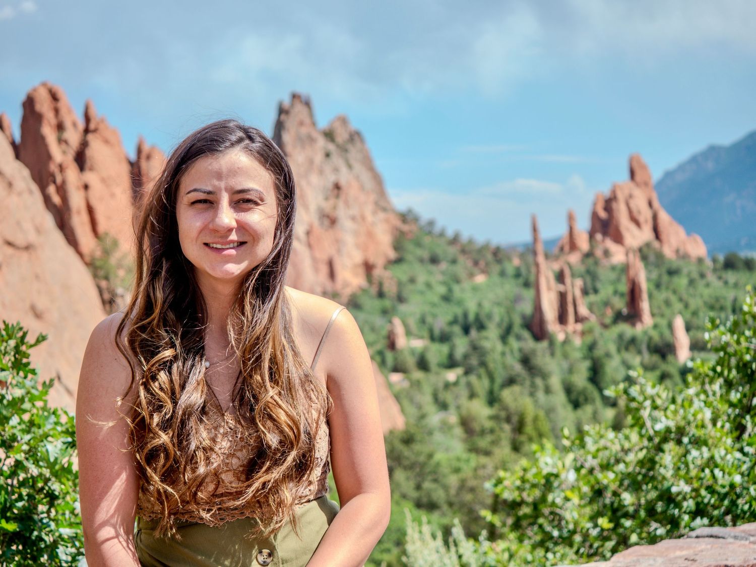 Scenic view of red rock formations at Garden of the Gods park in Colorado Springs with lush green vegetation.