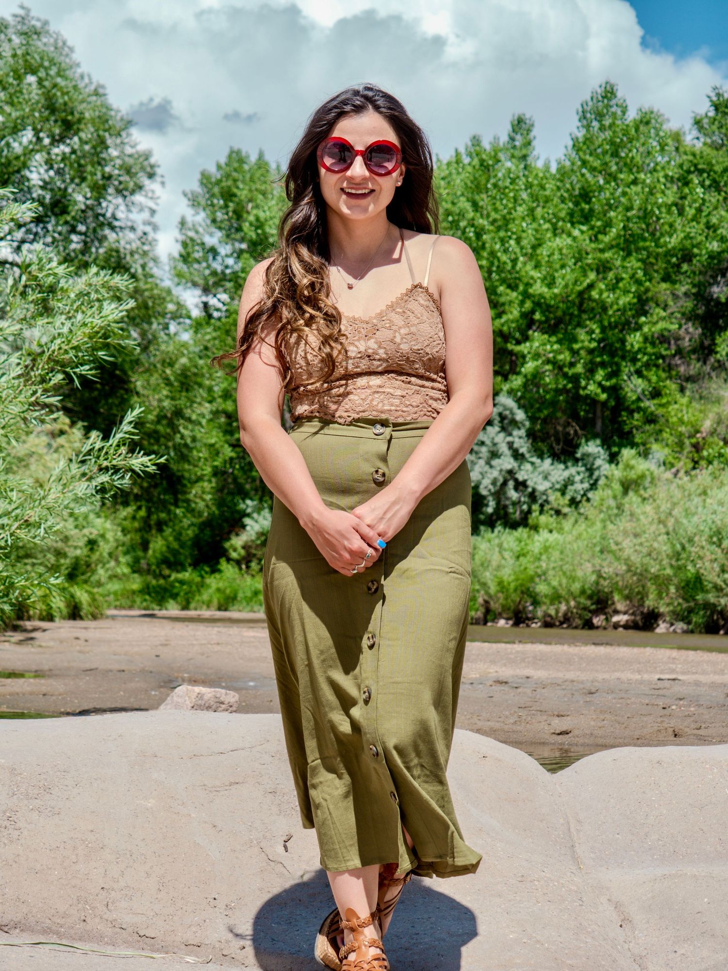 Fashionable summer outfit with brown crop top and olive green pants styled with sunglasses in a sunny outdoor setting.