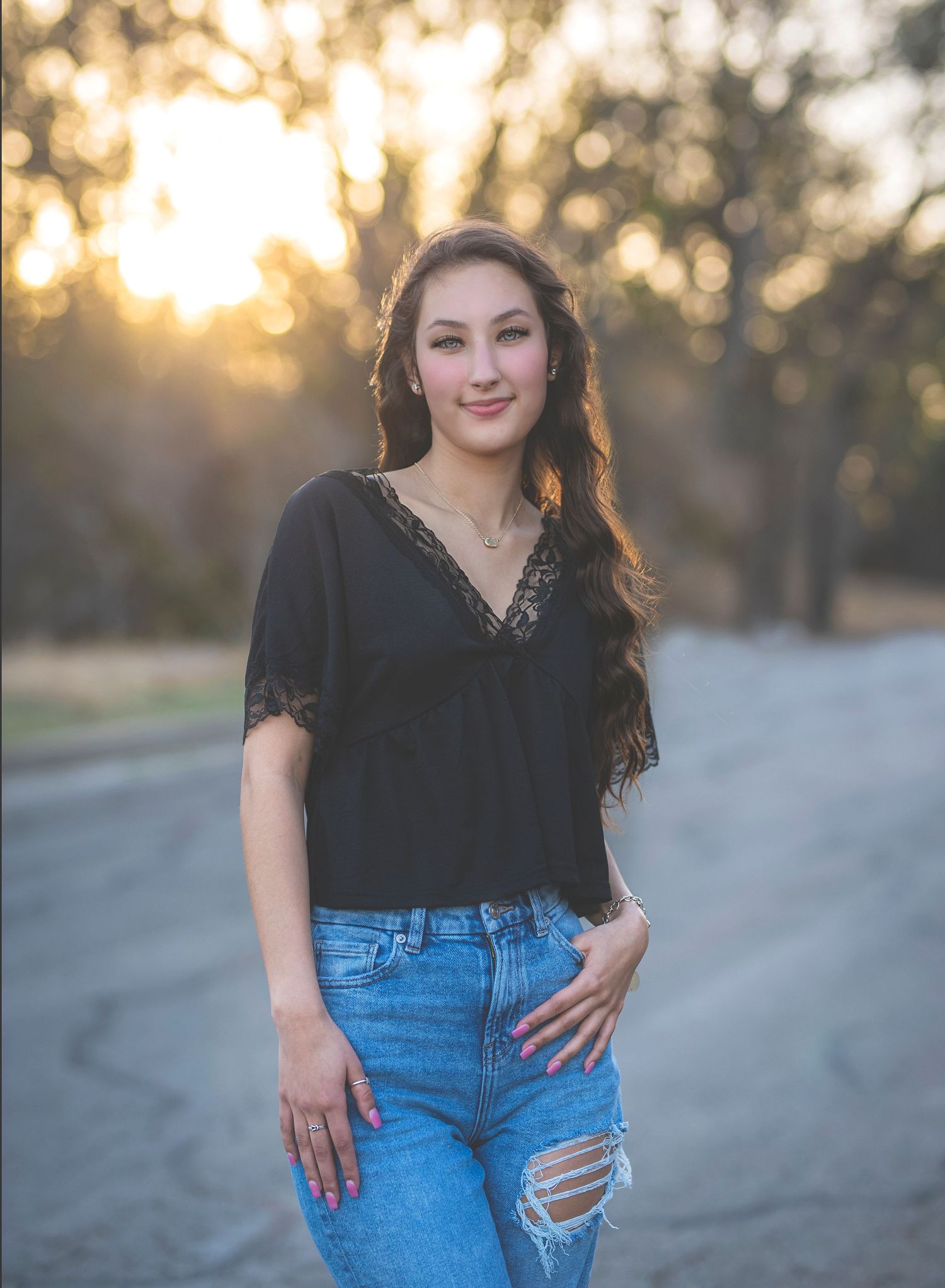 Casual outdoor portrait session in casual black top and distressed denim jeans at sunset.