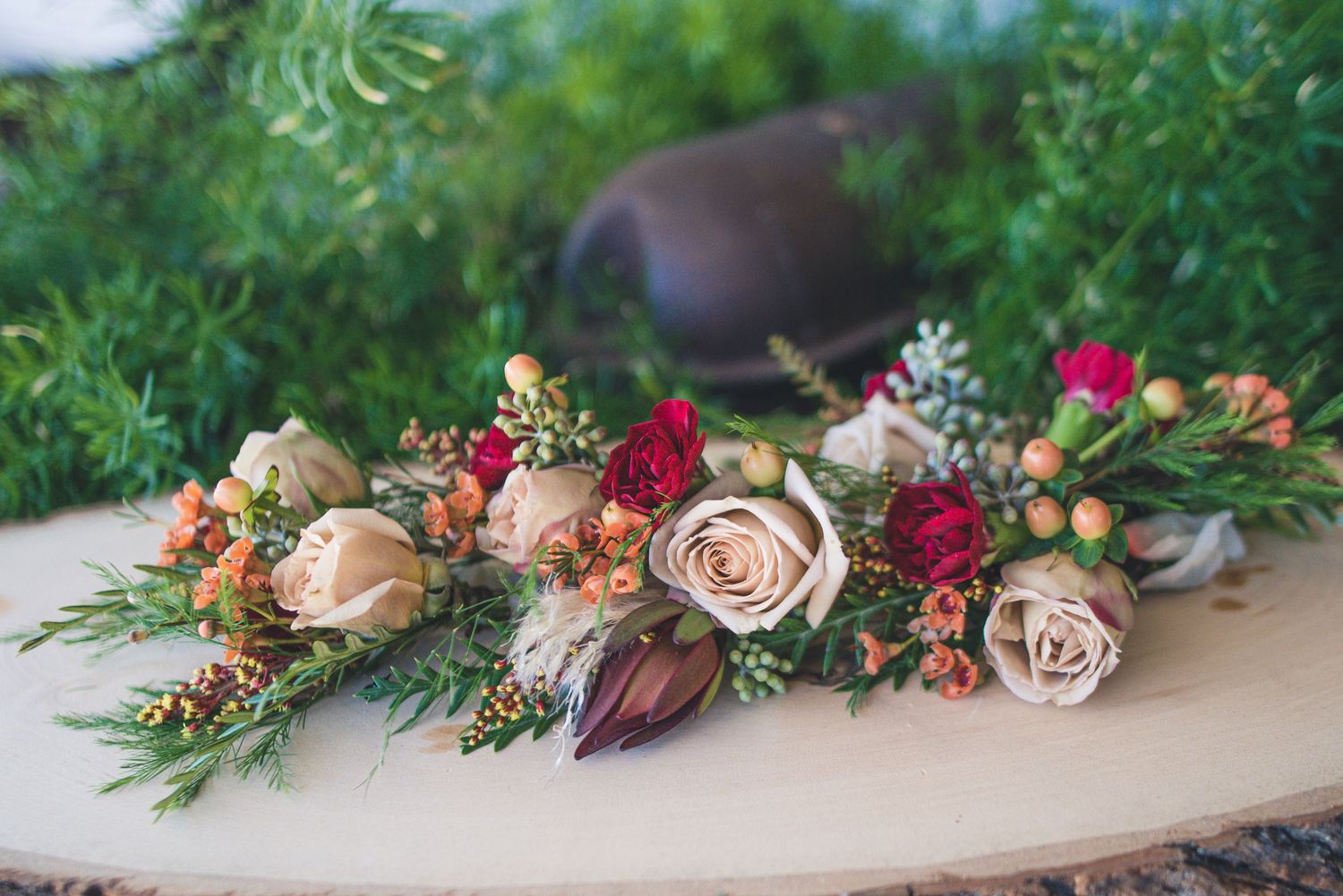 Romantic floral arrangement with roses and greenery on wooden surface.