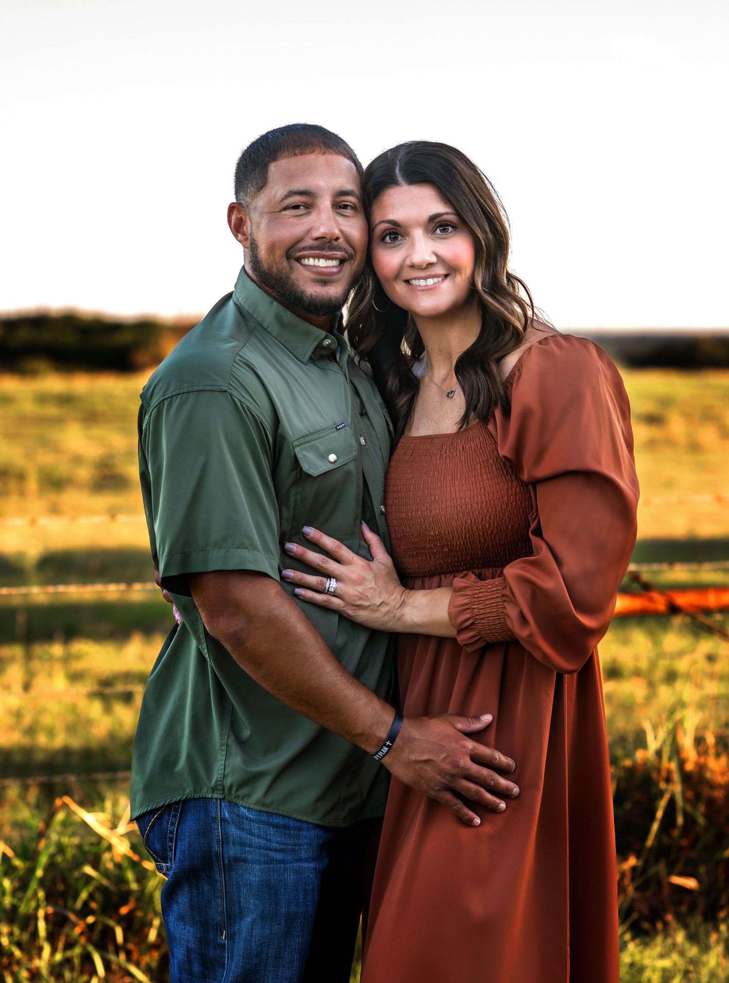 Couple embraces while wearing coordinating outfits during sunset photo session.
