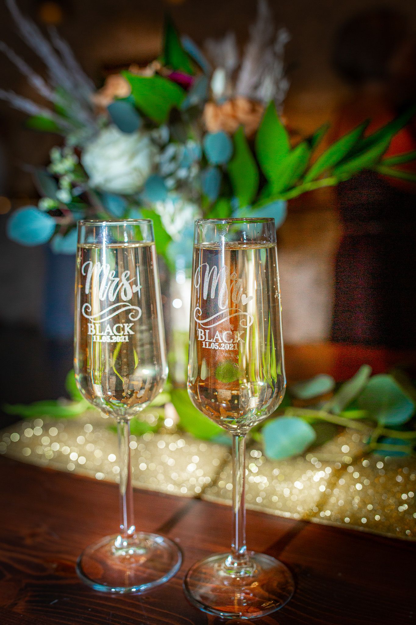 Elegant wine glasses with custom wedding monograms displayed with floral decor.