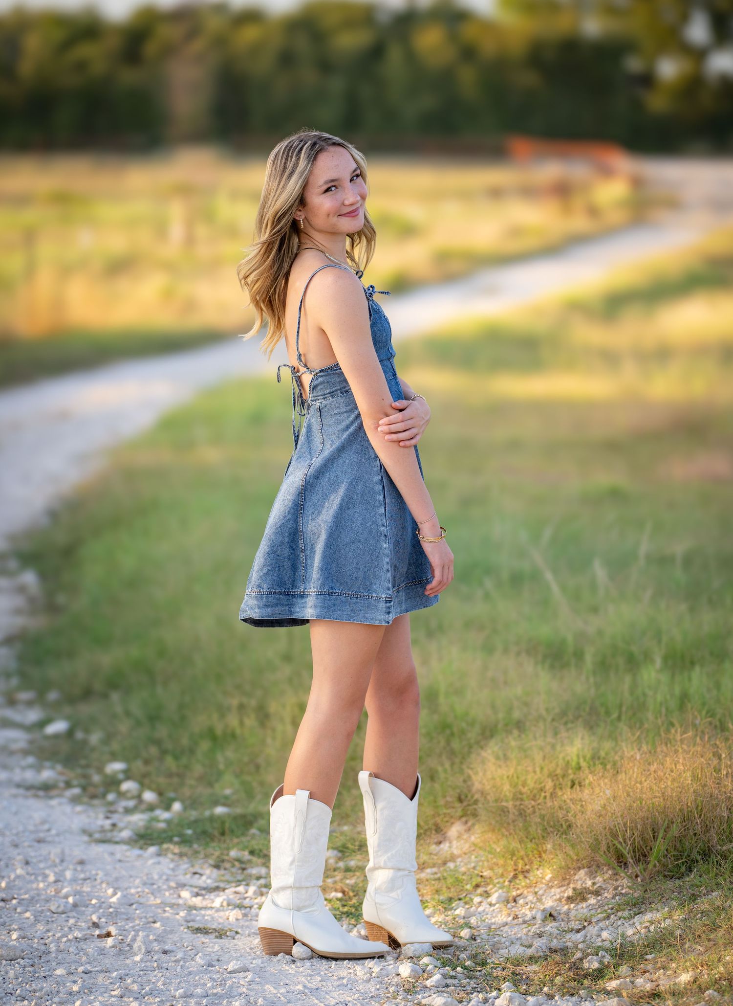 A series of photos showing someone in denim and white boots walking along a gravel path in a golden sunlit field.