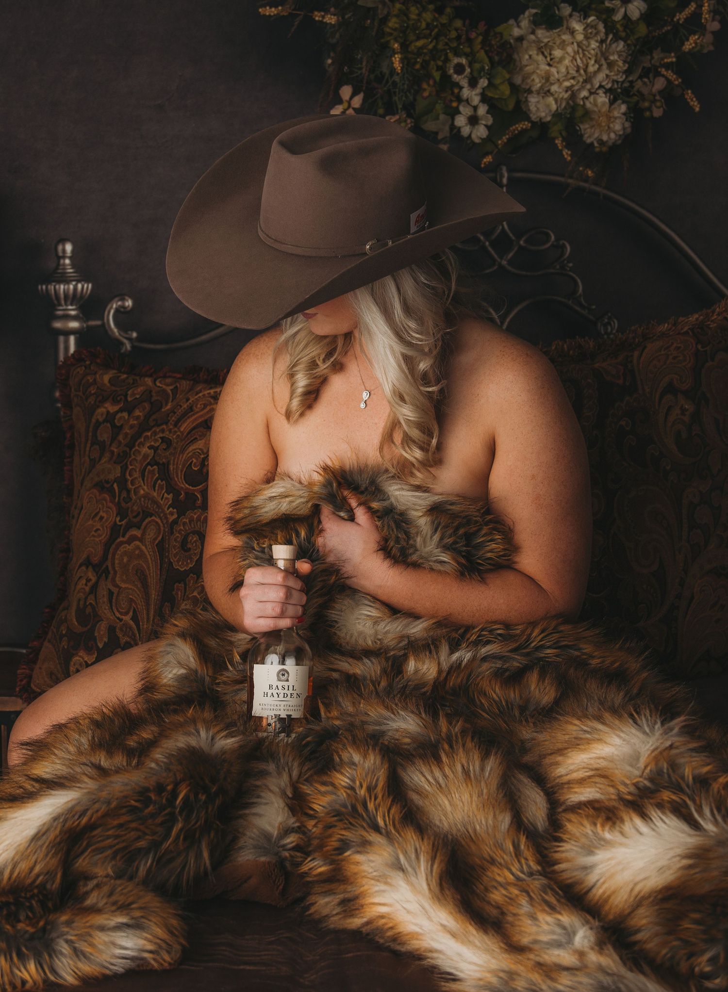 Rustic styled photo with fur blanket and brown cowboy hat in moody lighting.