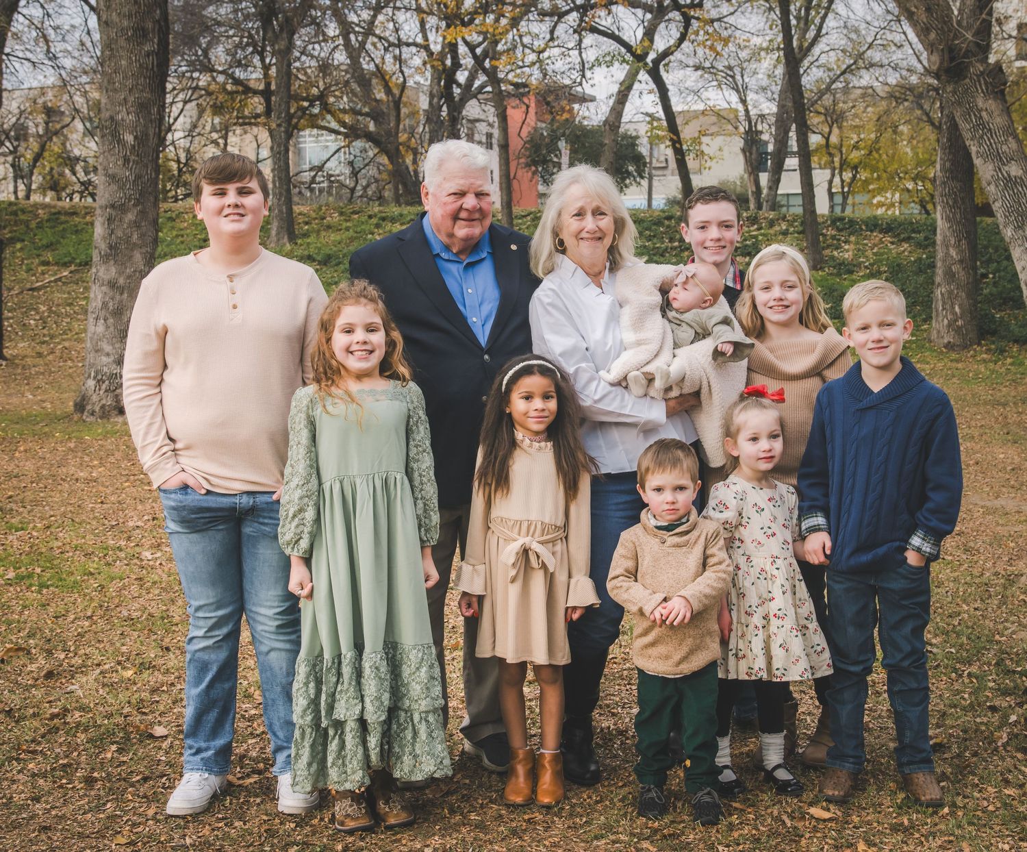 Extended family gathered for a fall portrait with coordinated neutral-colored outfits.