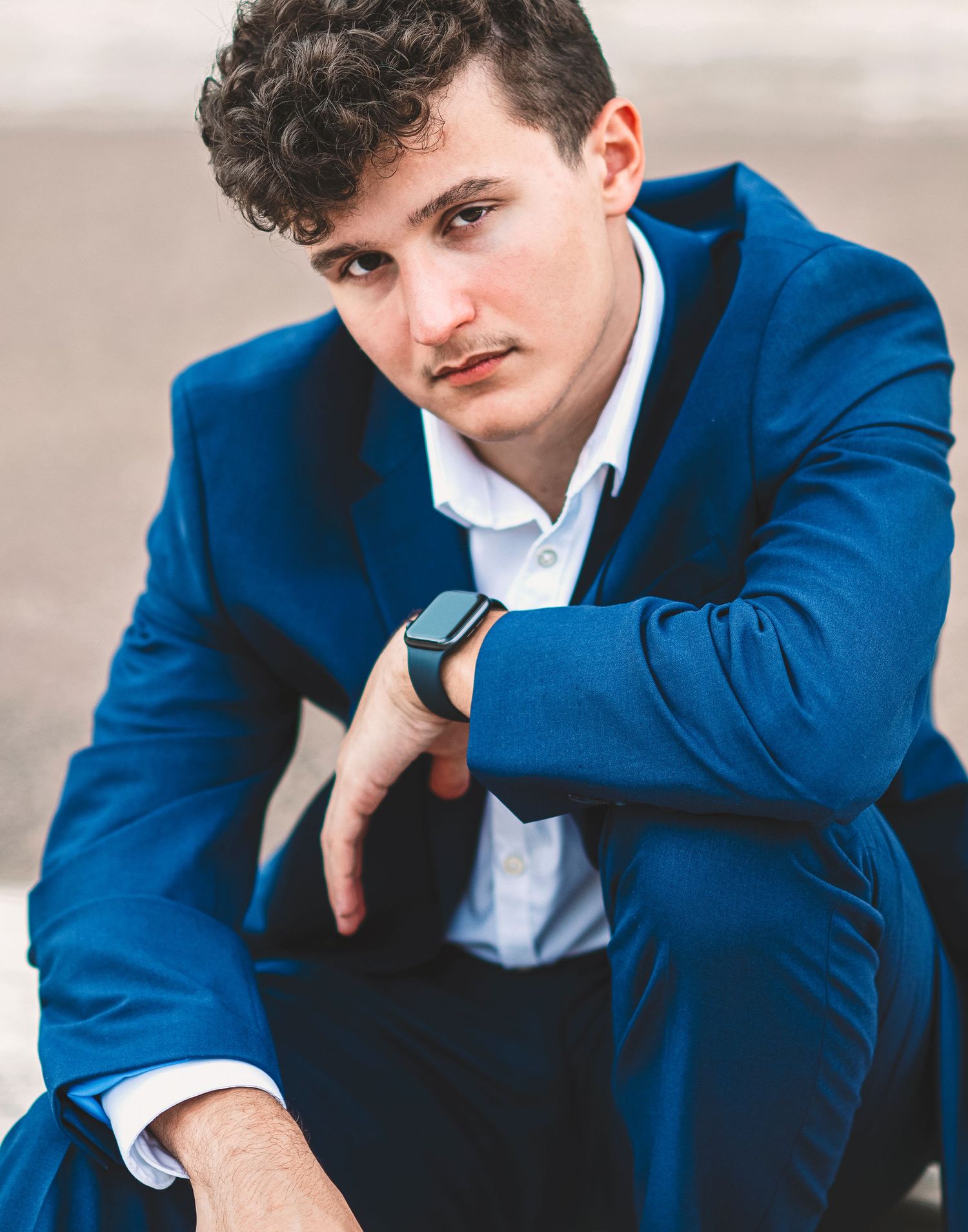 Fashion portrait series of man in blue suit and white shirt against light backdrop.