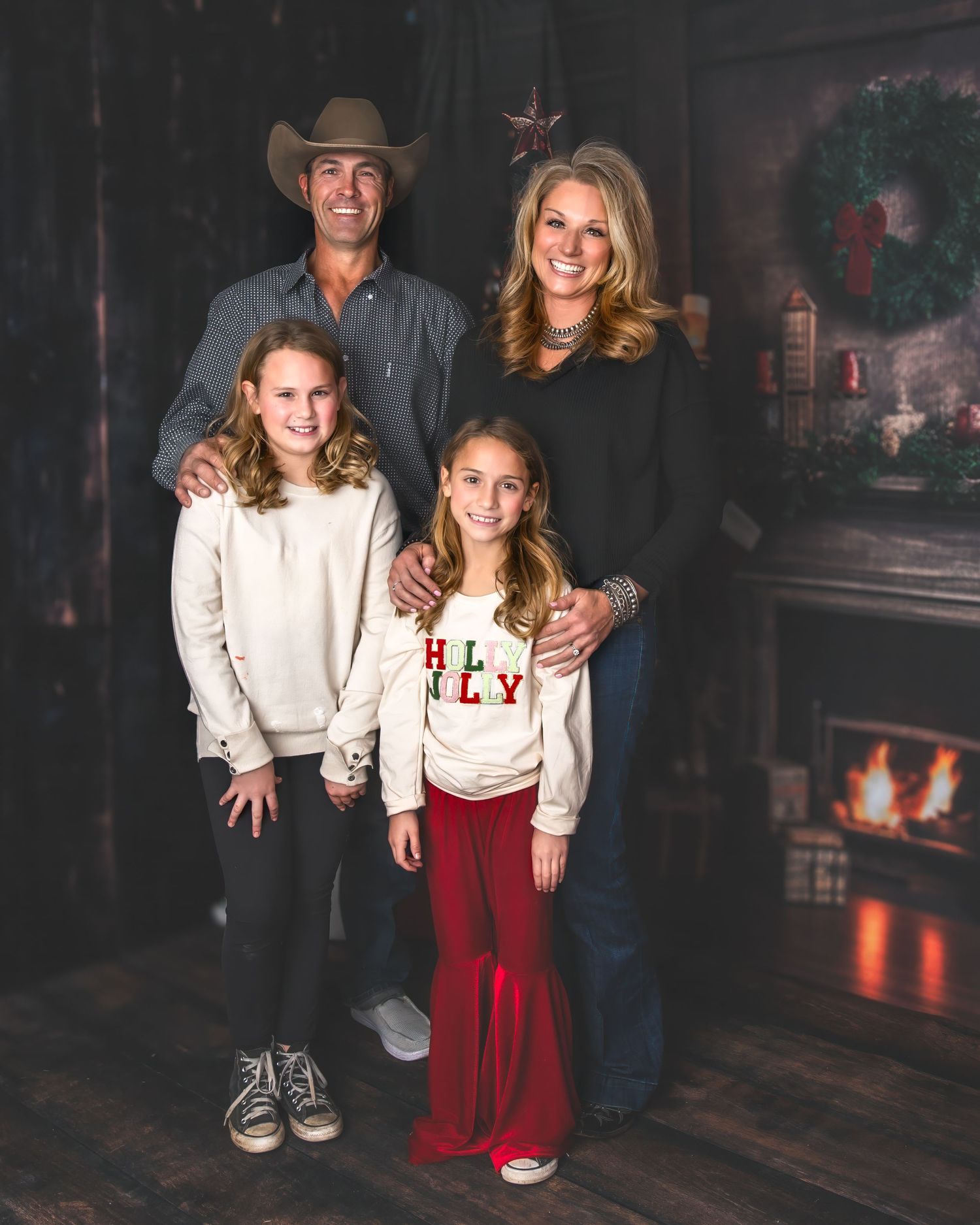 Family in western attire poses for holiday portrait by fireplace.