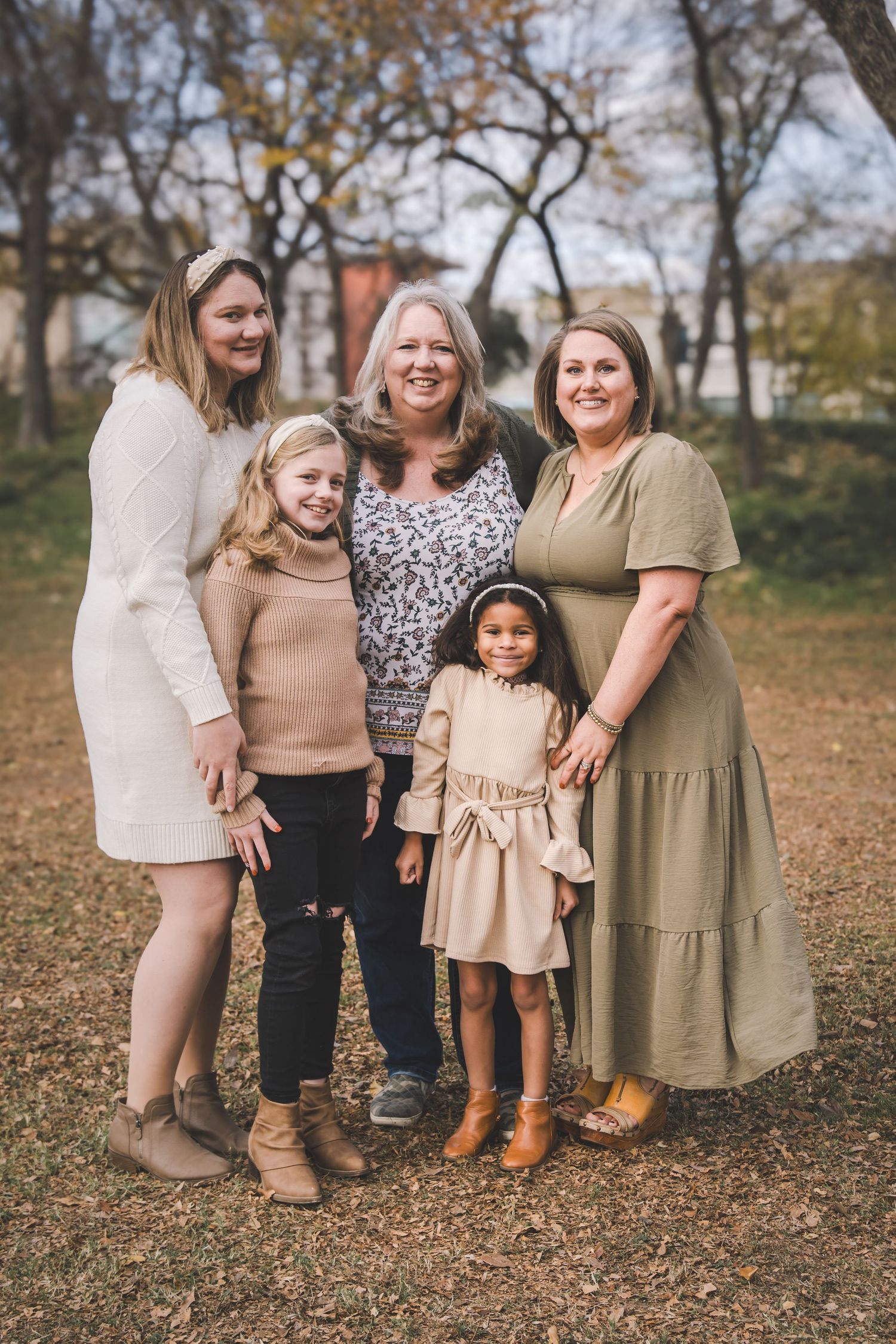 Multi-generational family portrait in casual attire against an autumn backdrop.