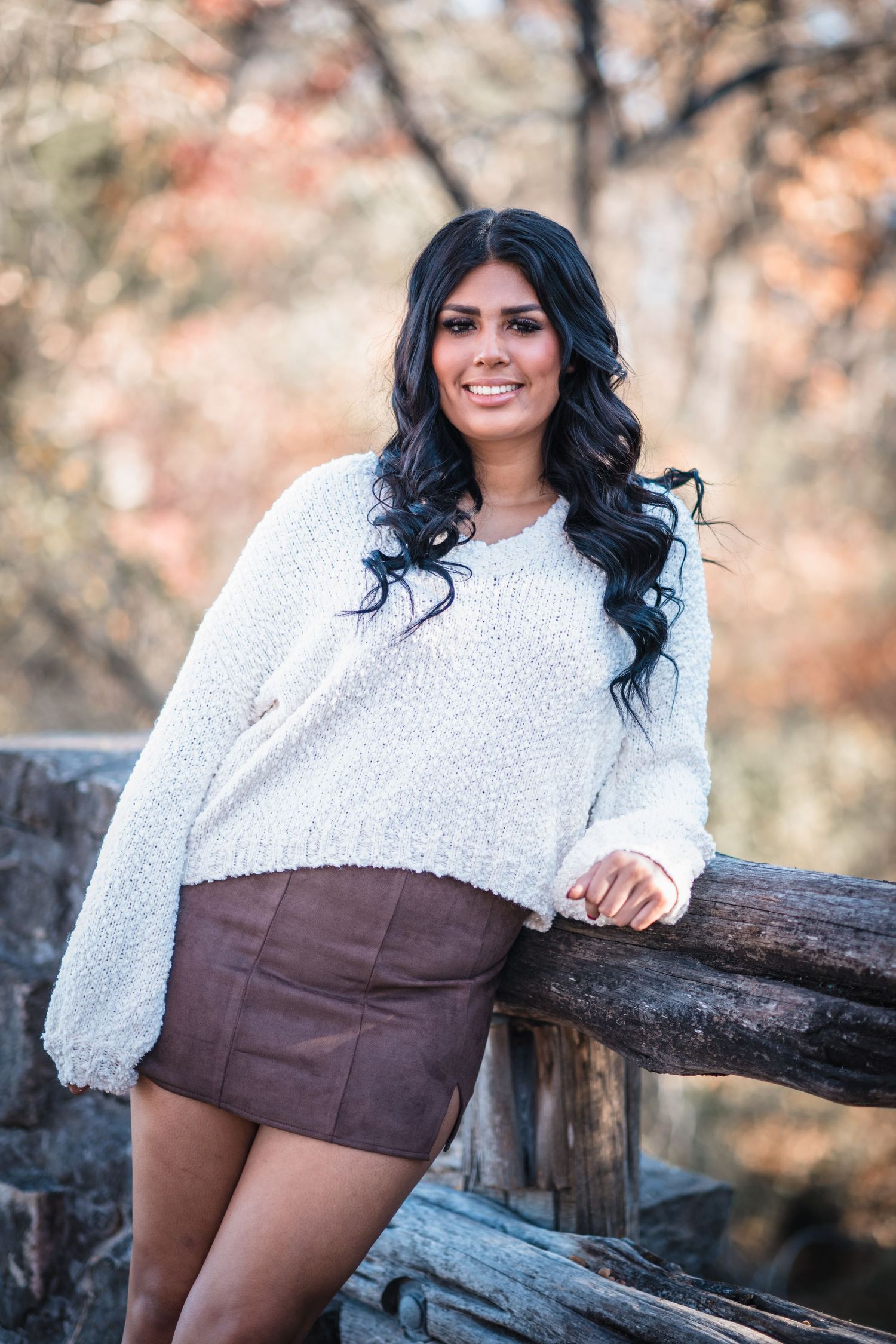 Fall portrait on wooden fence with autumn colors in background.