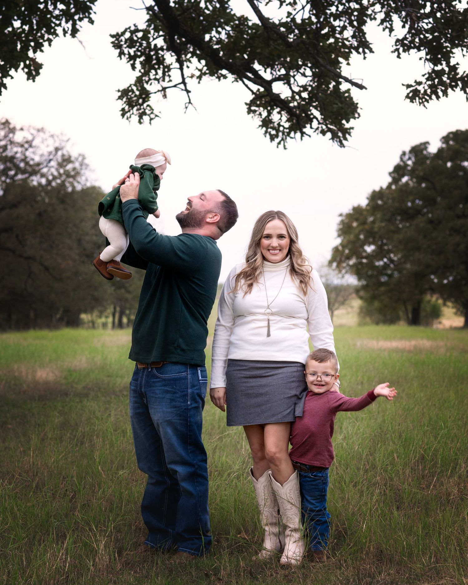 Family playing and spinning together in open field during casual photo session.