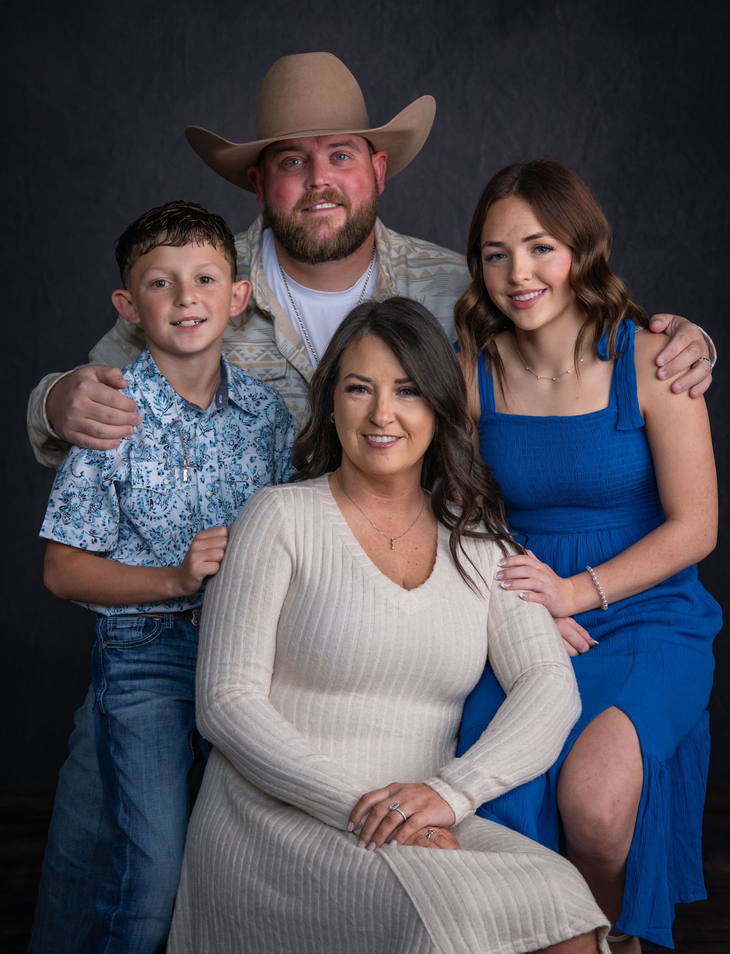A family portrait session in a studio with blue and white outfits against a dark background.