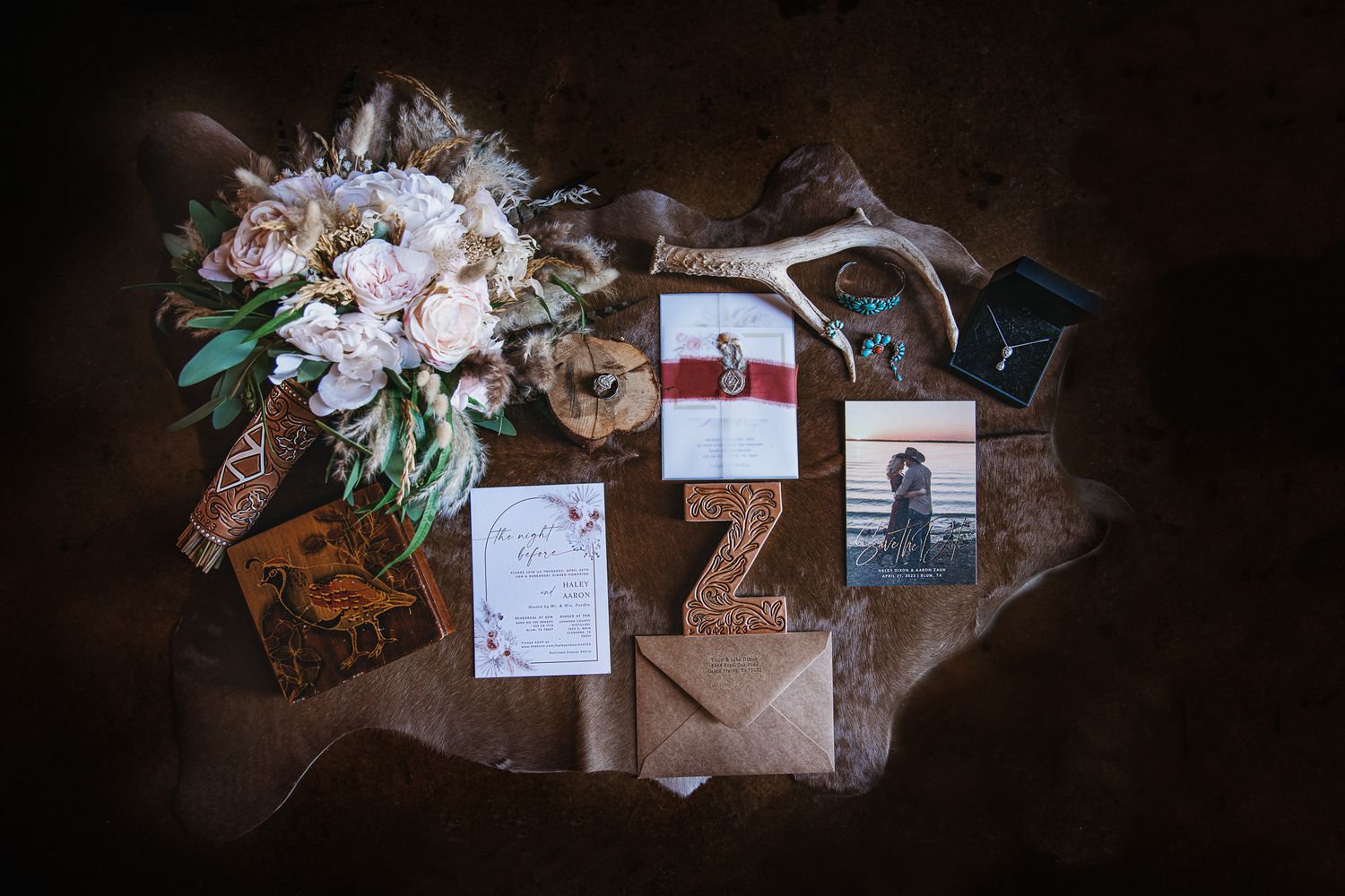 Wedding invitation suite with floral elements and envelopes arranged on textured background.