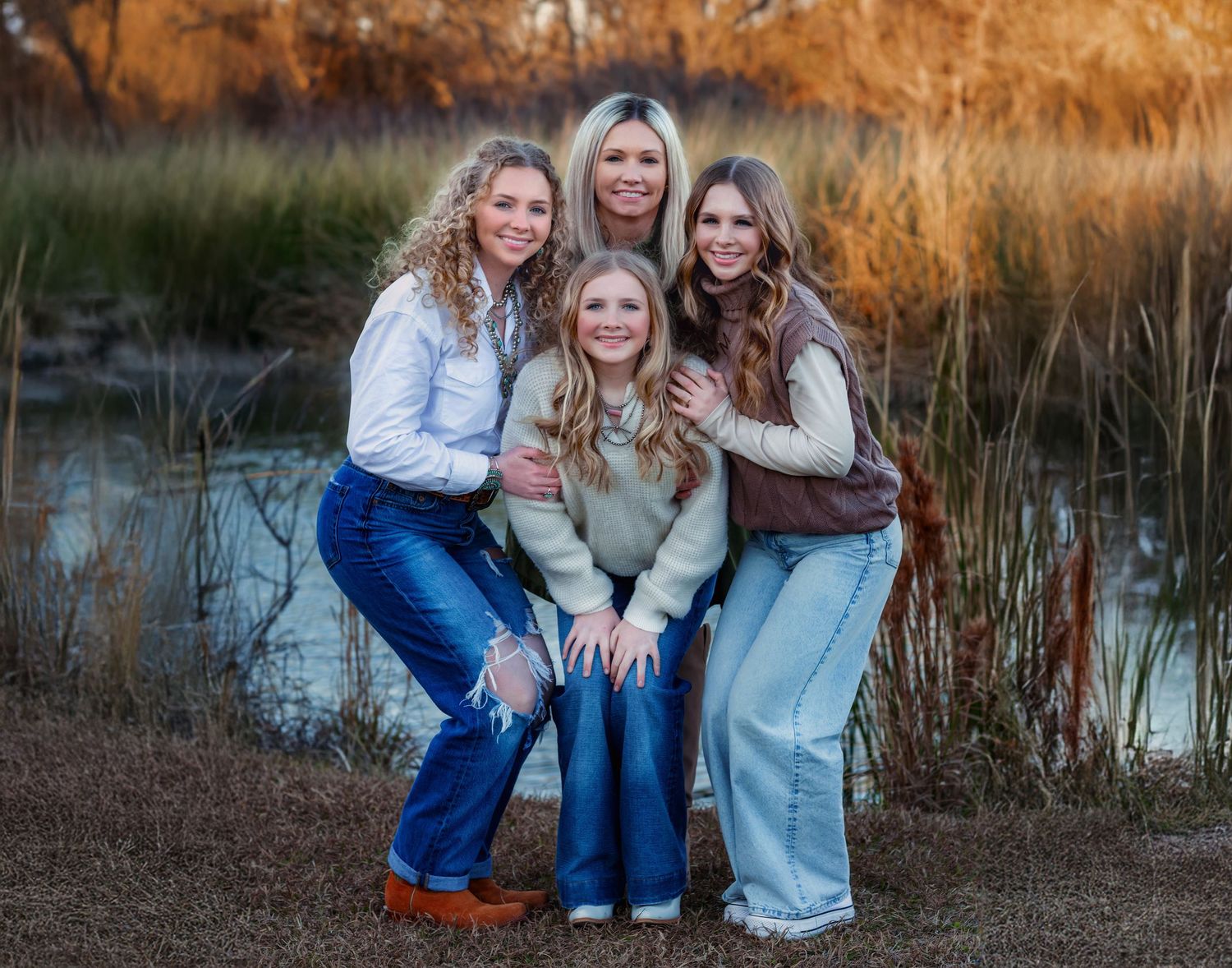 A casual outdoor family photo by a pond during golden hour.