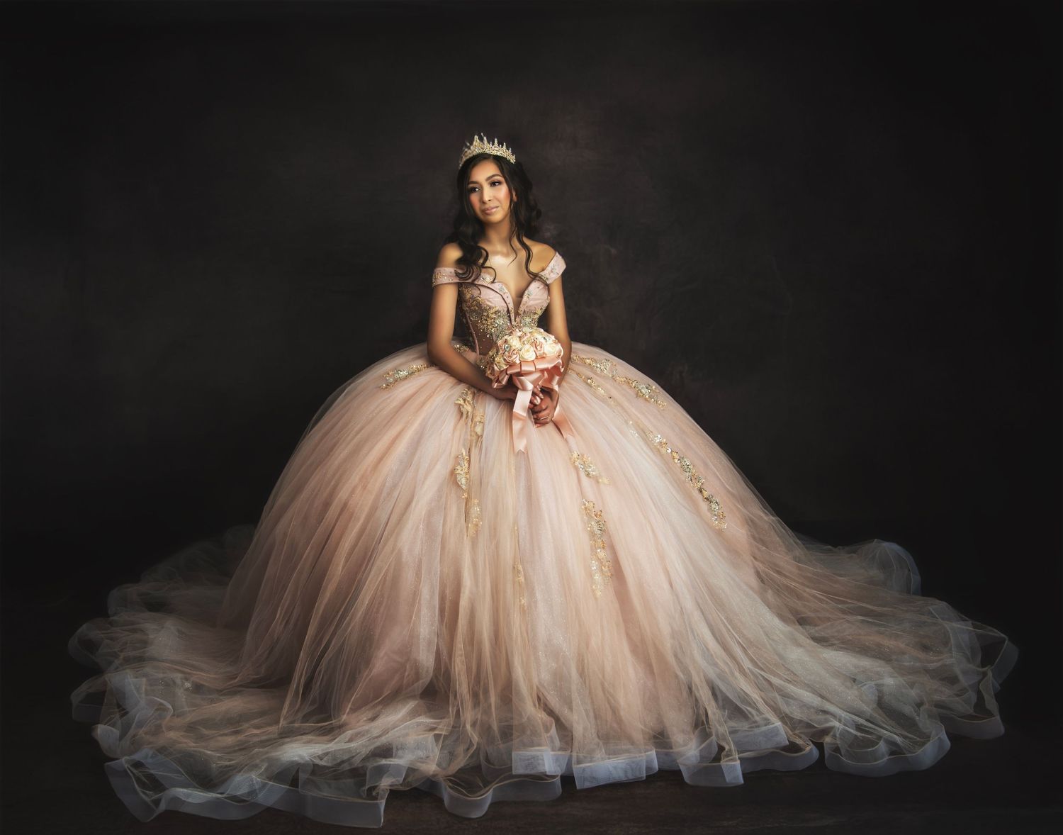 Dramatic portrait series of a princess in a flowing champagne tulle ball gown against a dark background.