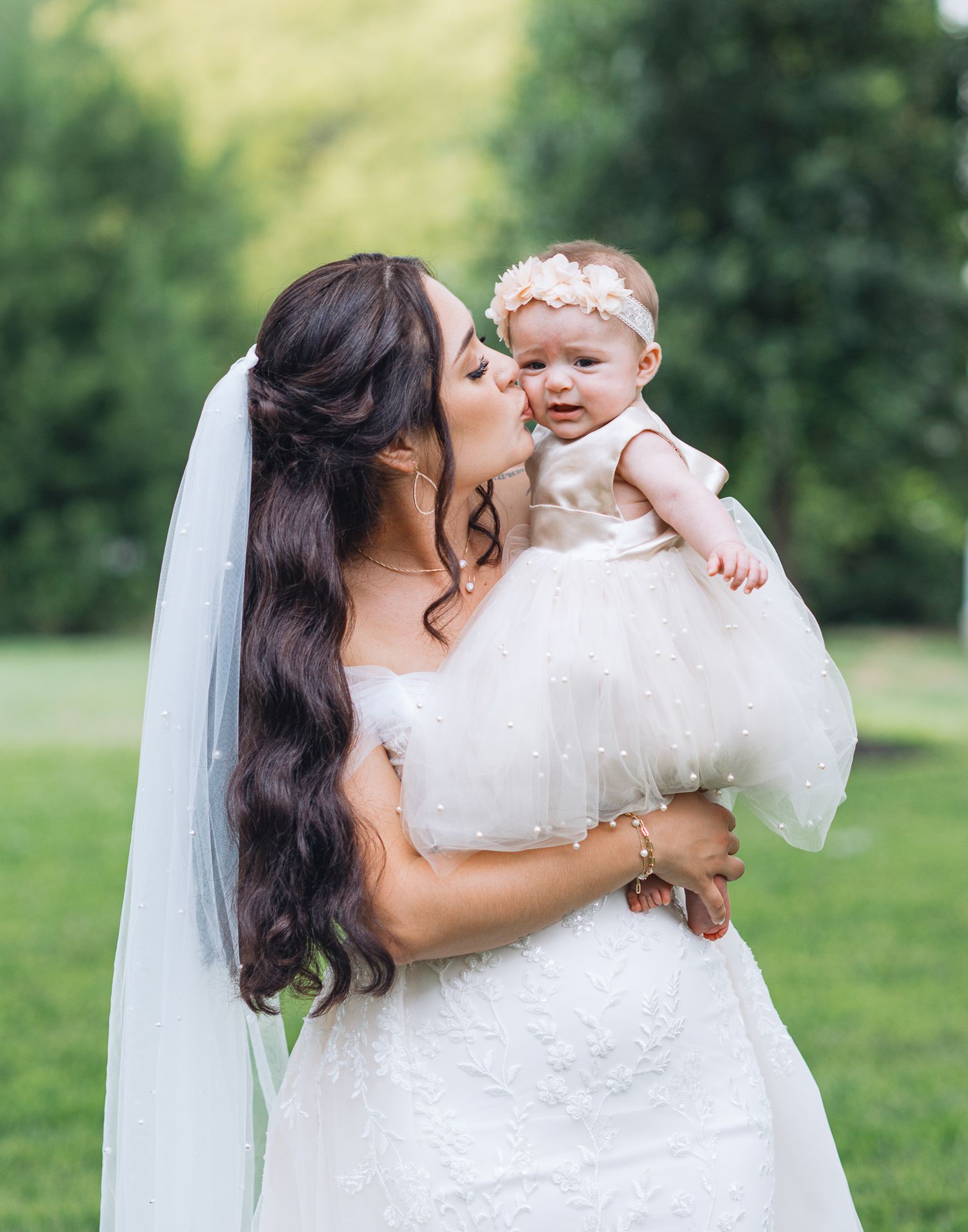 A tender moment captured between a bride in white and a small child in an outdoor setting.