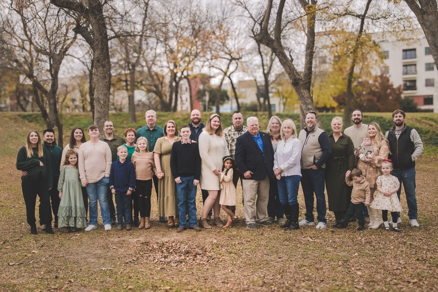 Large extended family group photo taken outdoors in autumn setting.