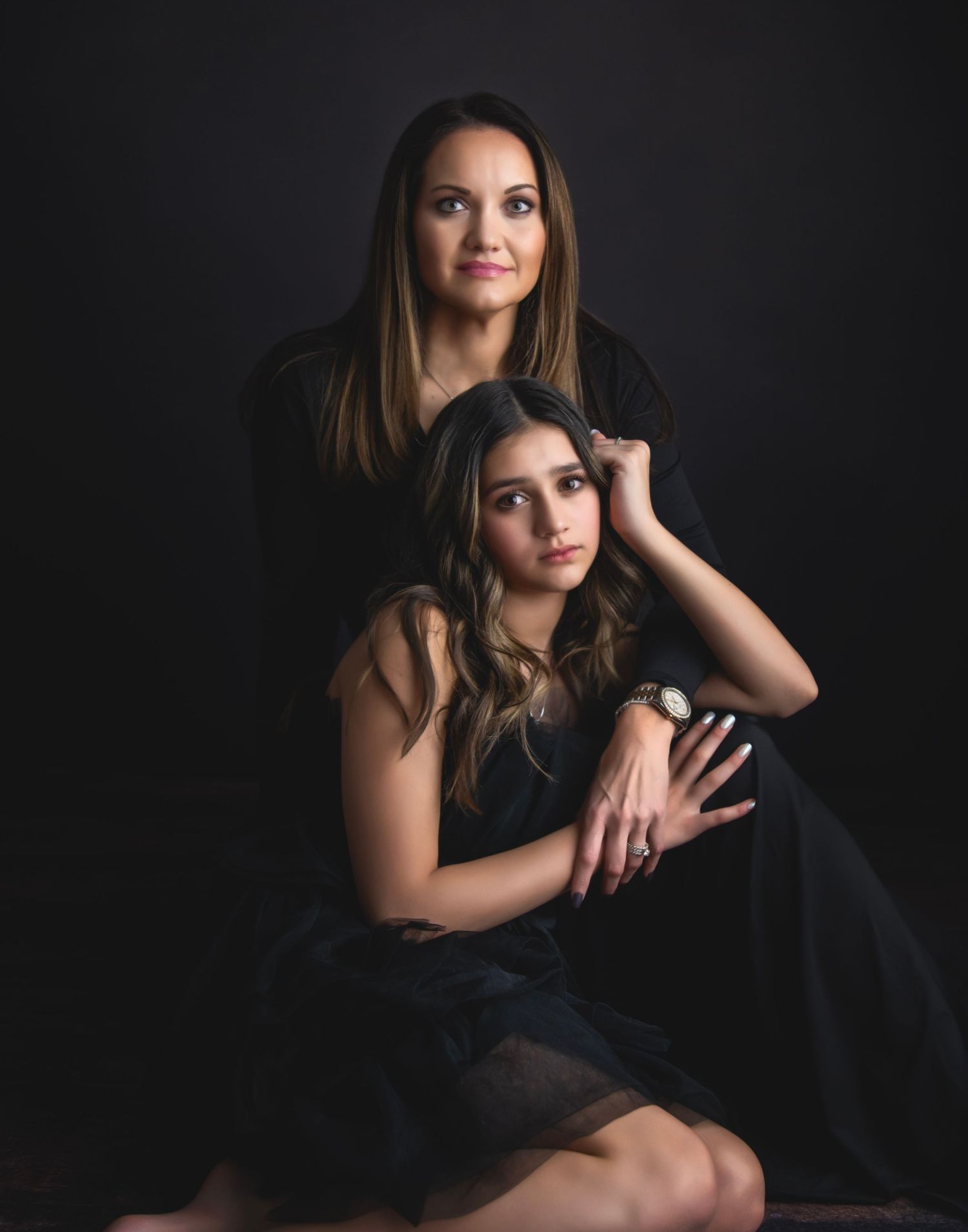 Studio portrait session with dramatic lighting and black backdrop featuring elegant poses.