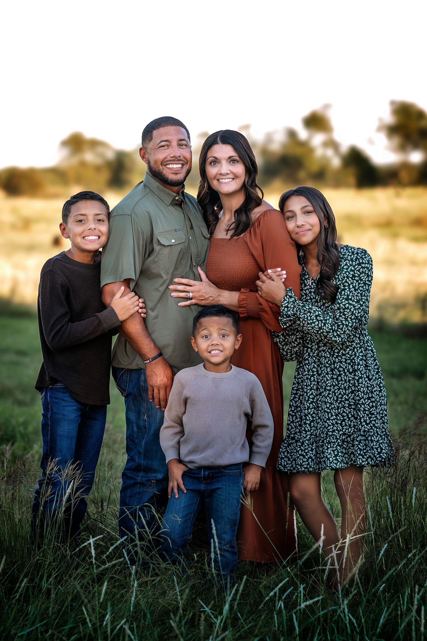 Family portrait in field with setting sun creates warm, intimate moment.