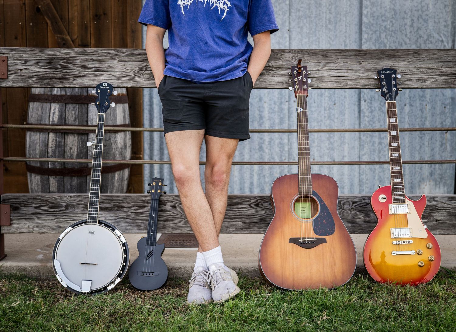 Musical instruments displayed on grass against a wooden and metal wall background.