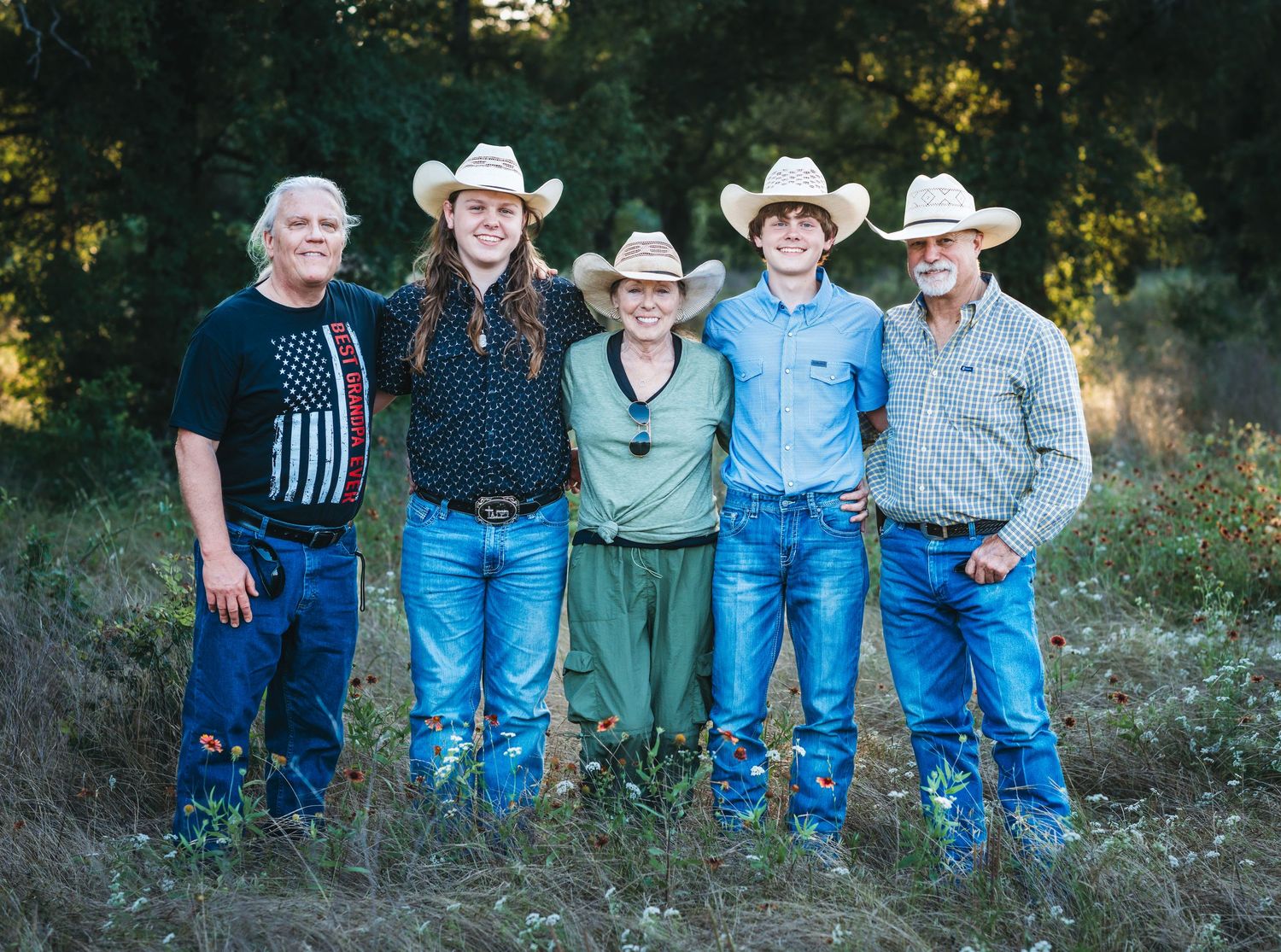 Group wearing western attire and cowboy hats posed together outdoors.