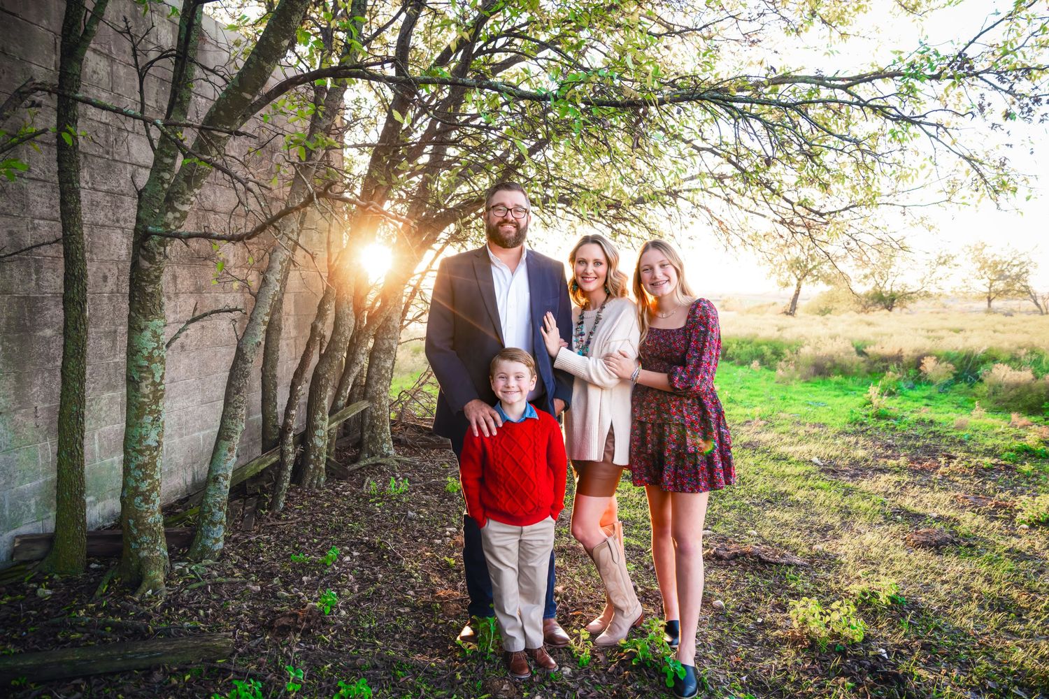 Family gathering under tree branches during golden hour sunset photography session.
